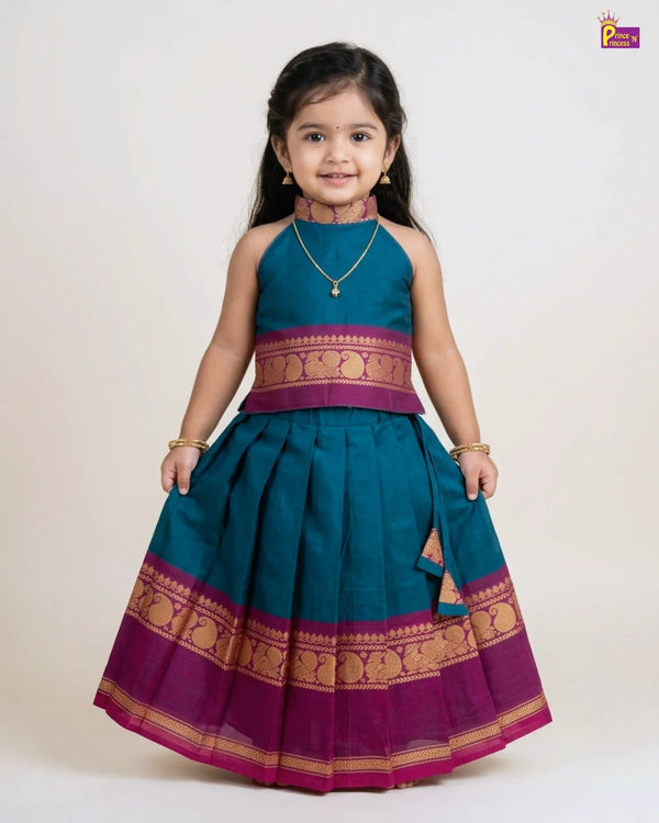 Young girl wearing a traditional teal and purple dress with gold accents on a white background