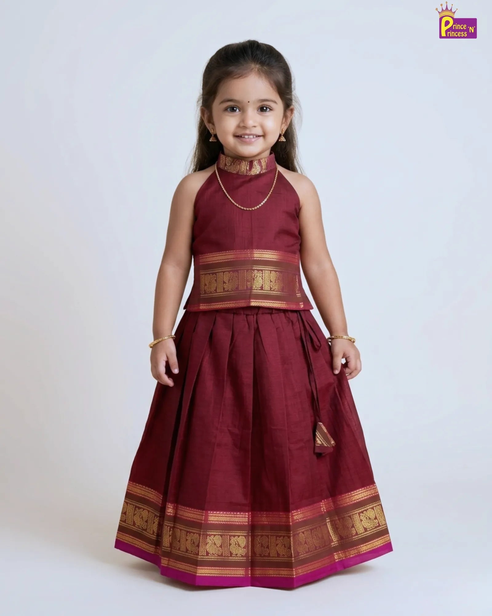Young girl wearing a maroon traditional dress with gold accents on a white background