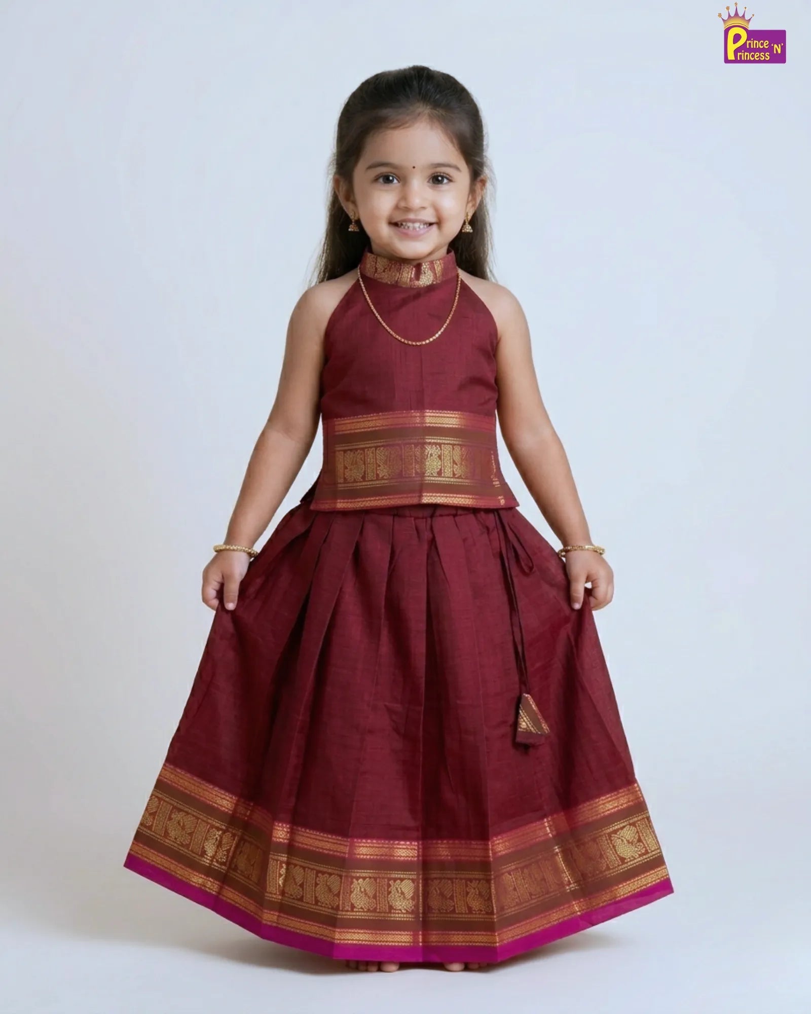 Young girl wearing a traditional maroon dress with gold accents on a white background