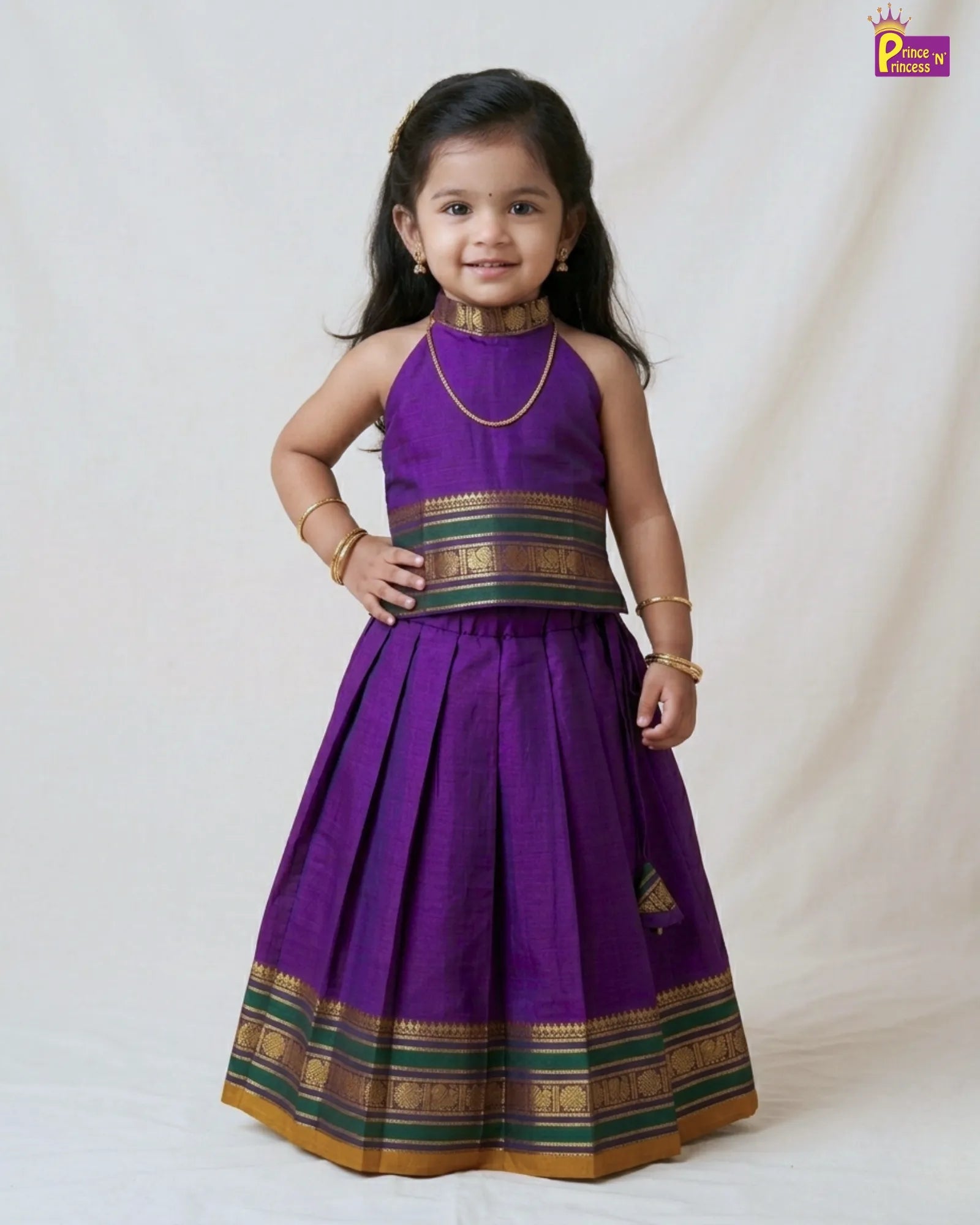 Young girl wearing a purple traditional outfit with gold and green accents on a white background