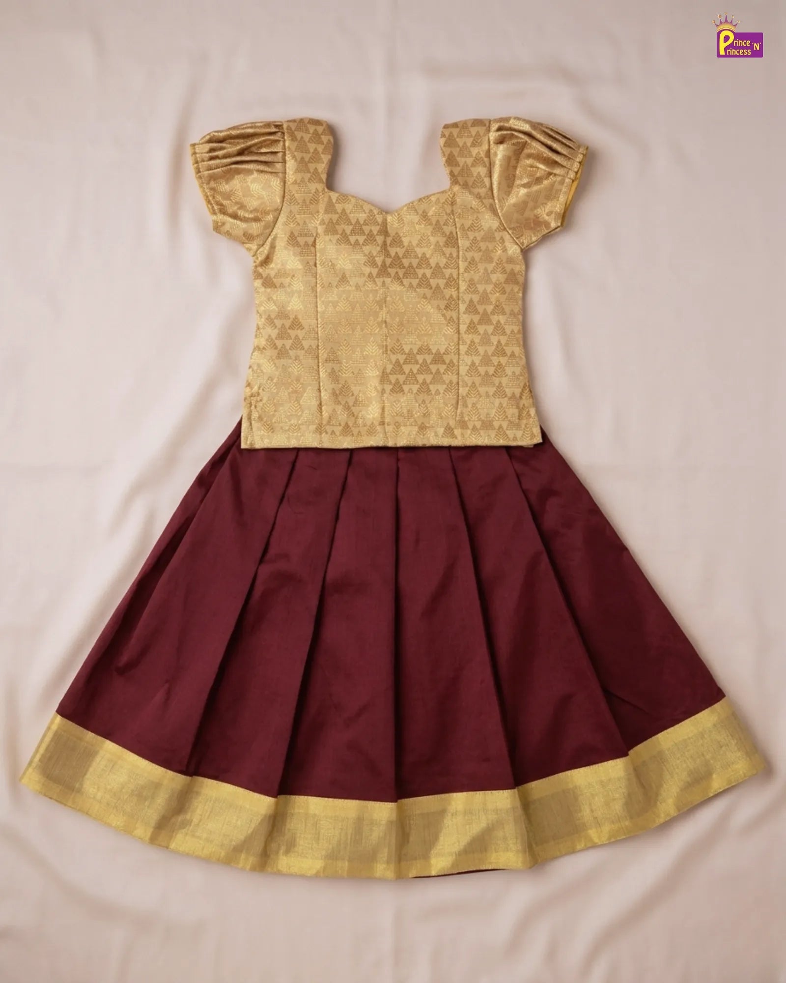 Gold blouse with maroon pleated skirt on a beige background
