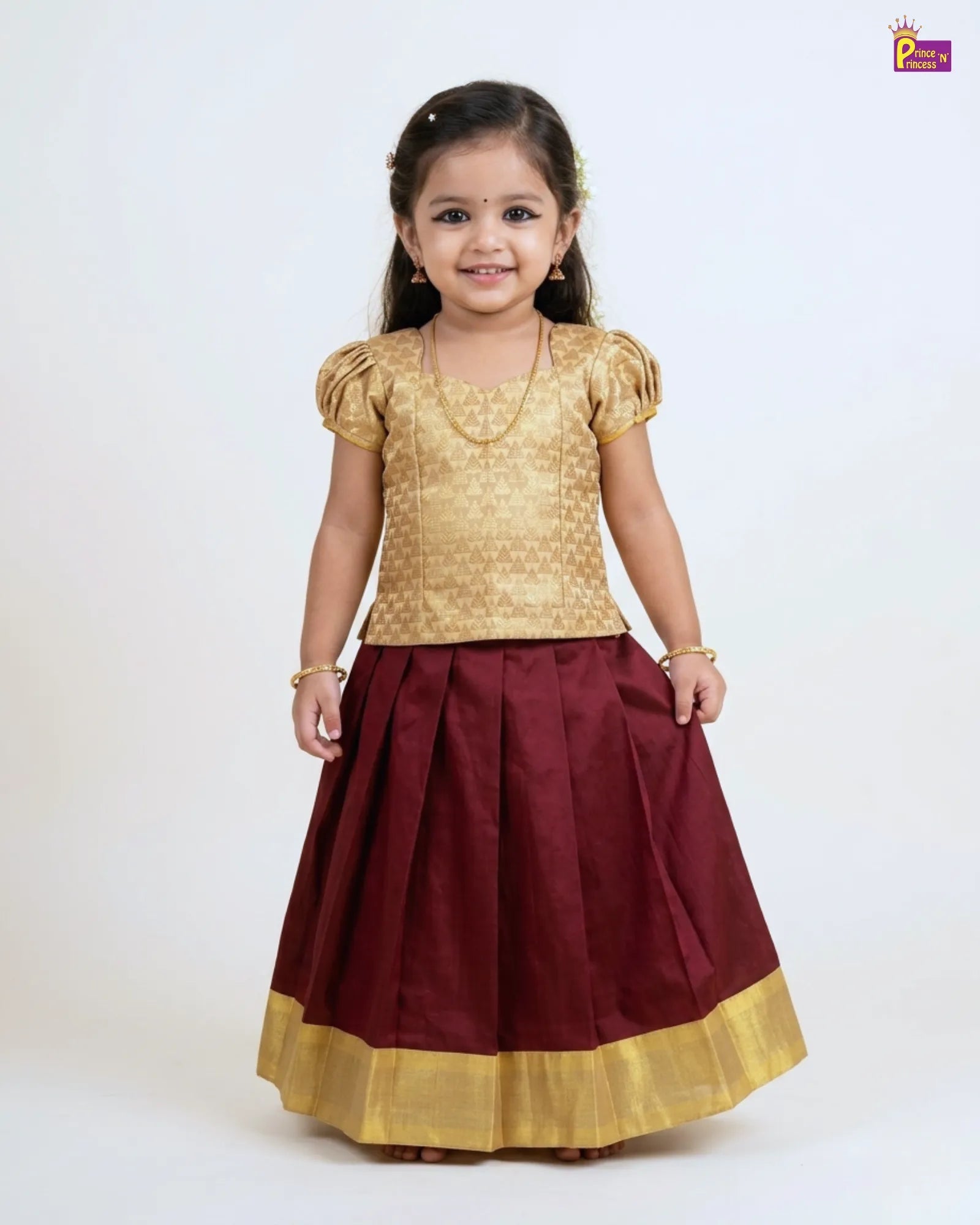 Young girl wearing a gold top and maroon skirt with gold hem on a white background