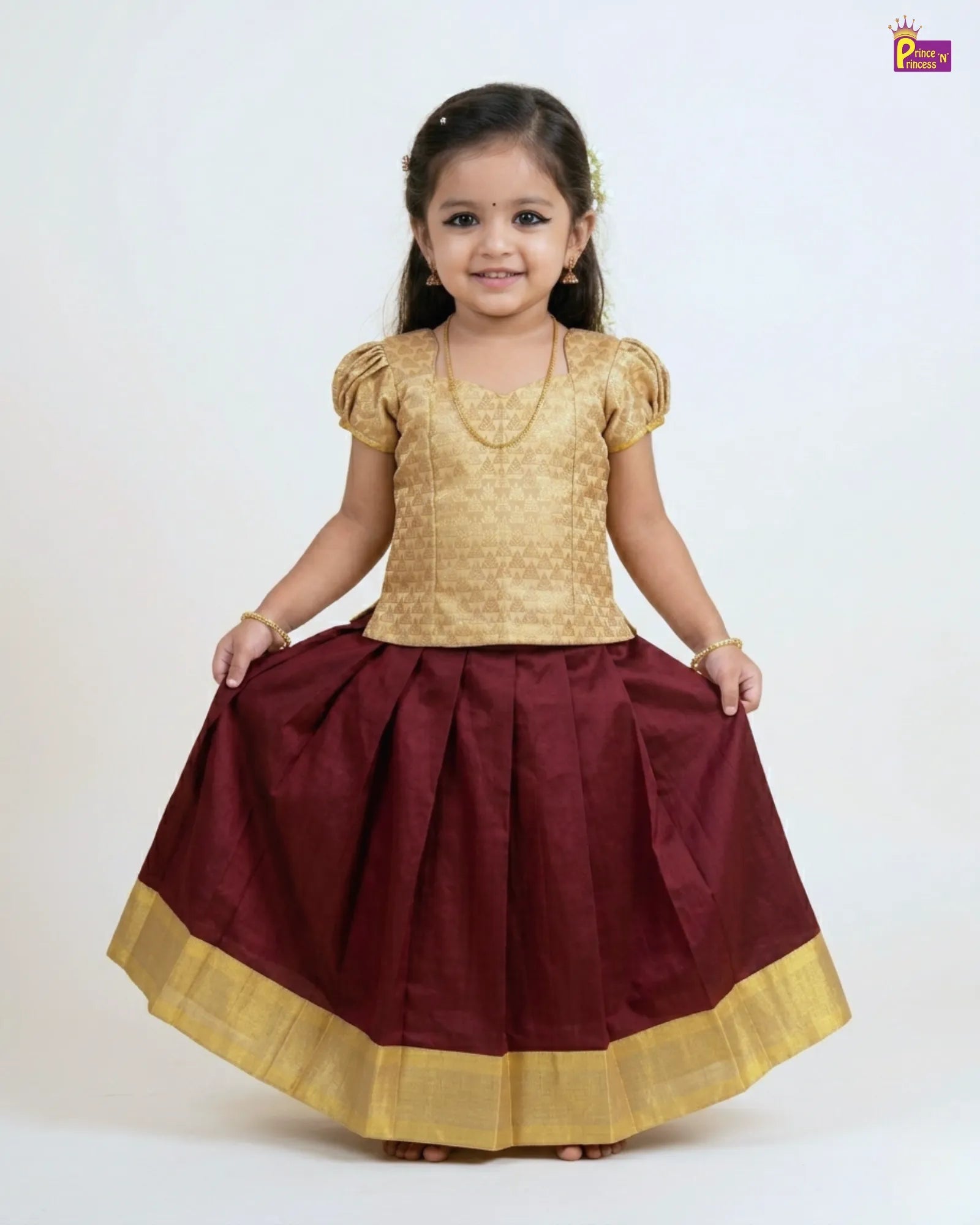 Young girl wearing a gold top and maroon skirt with gold trim on a white background