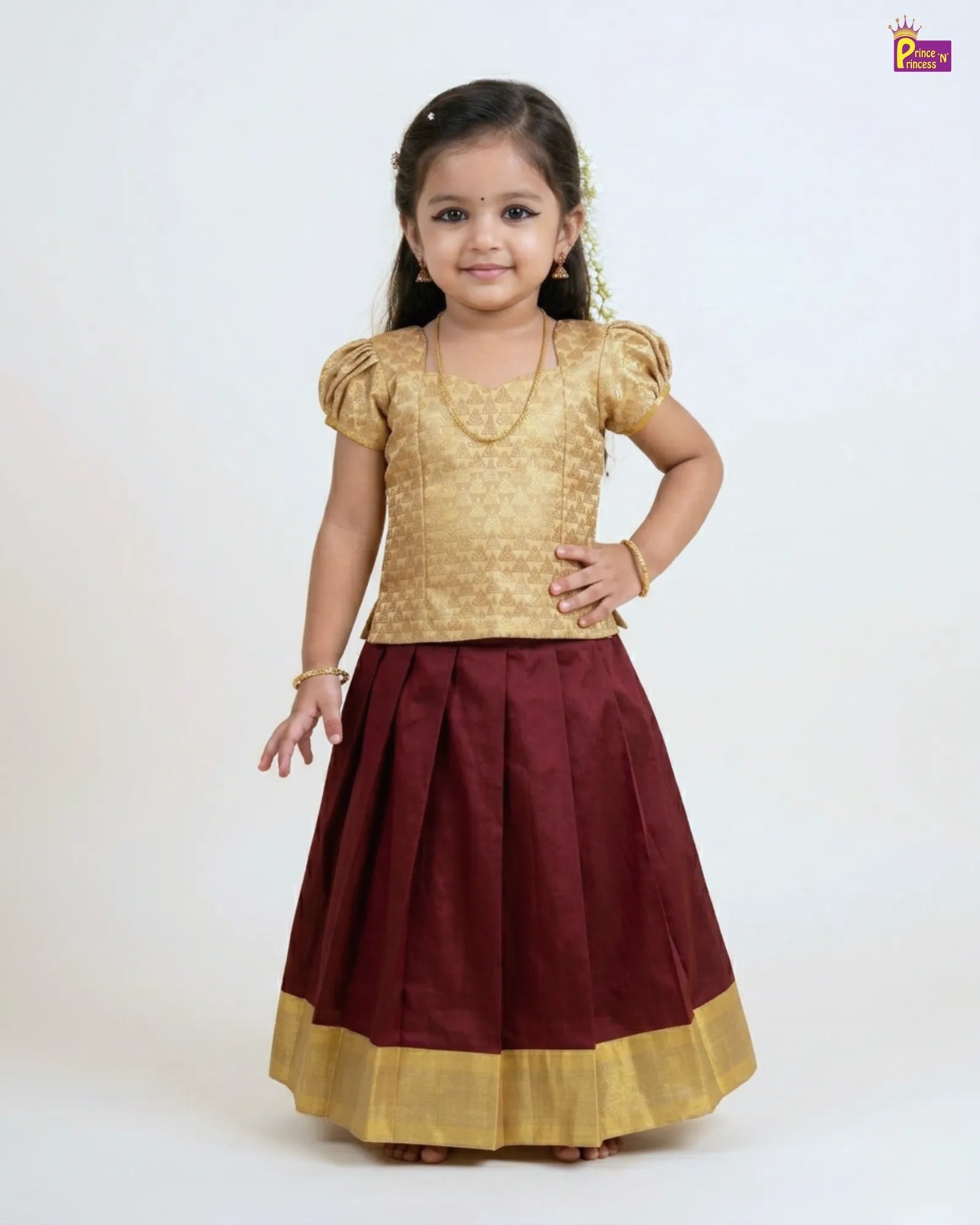 Young girl wearing a gold top and maroon skirt with gold border on a white background