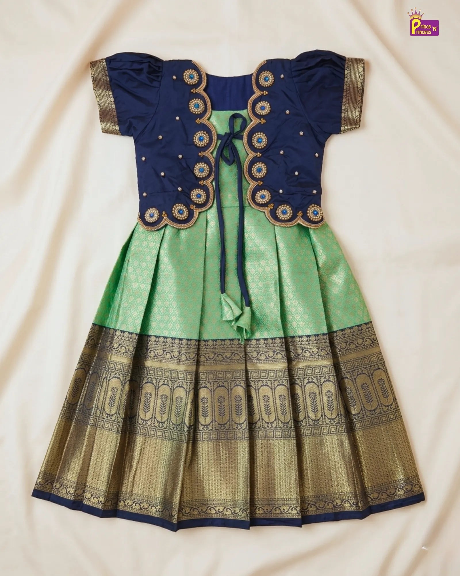 Traditional outfit with a blue top and green skirt on a beige background