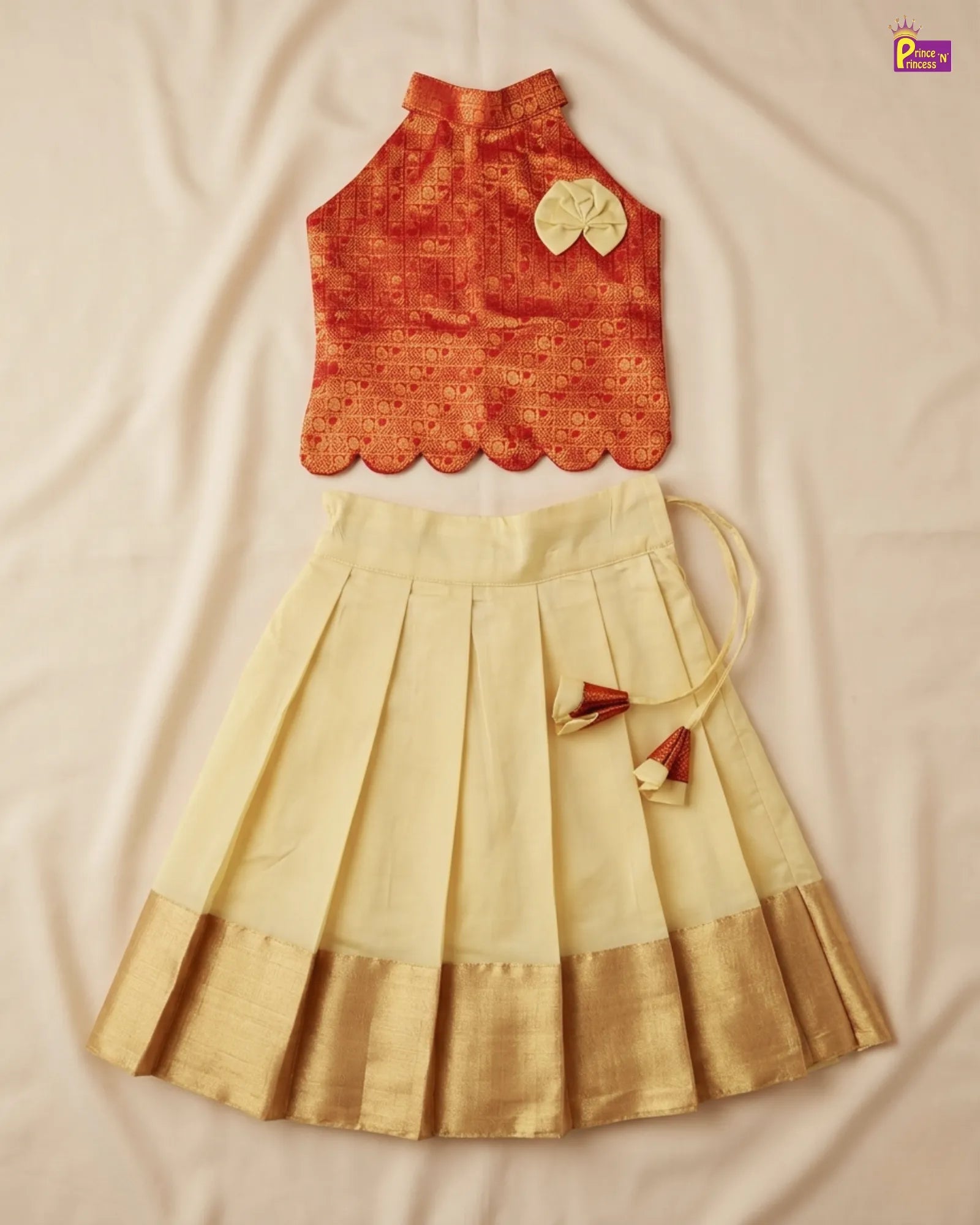Orange top and beige skirt with gold accents on a beige fabric background