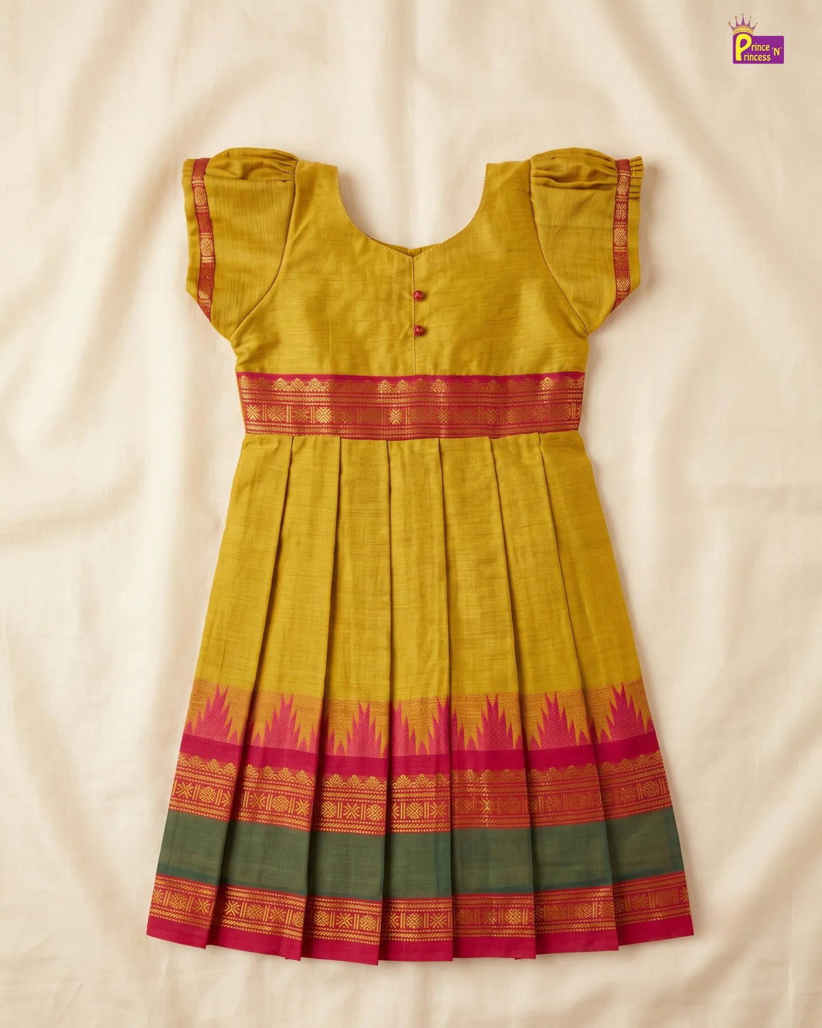 A yellow cotton saree dress with a red and pink border, laid flat on a cream-colored fabric background.