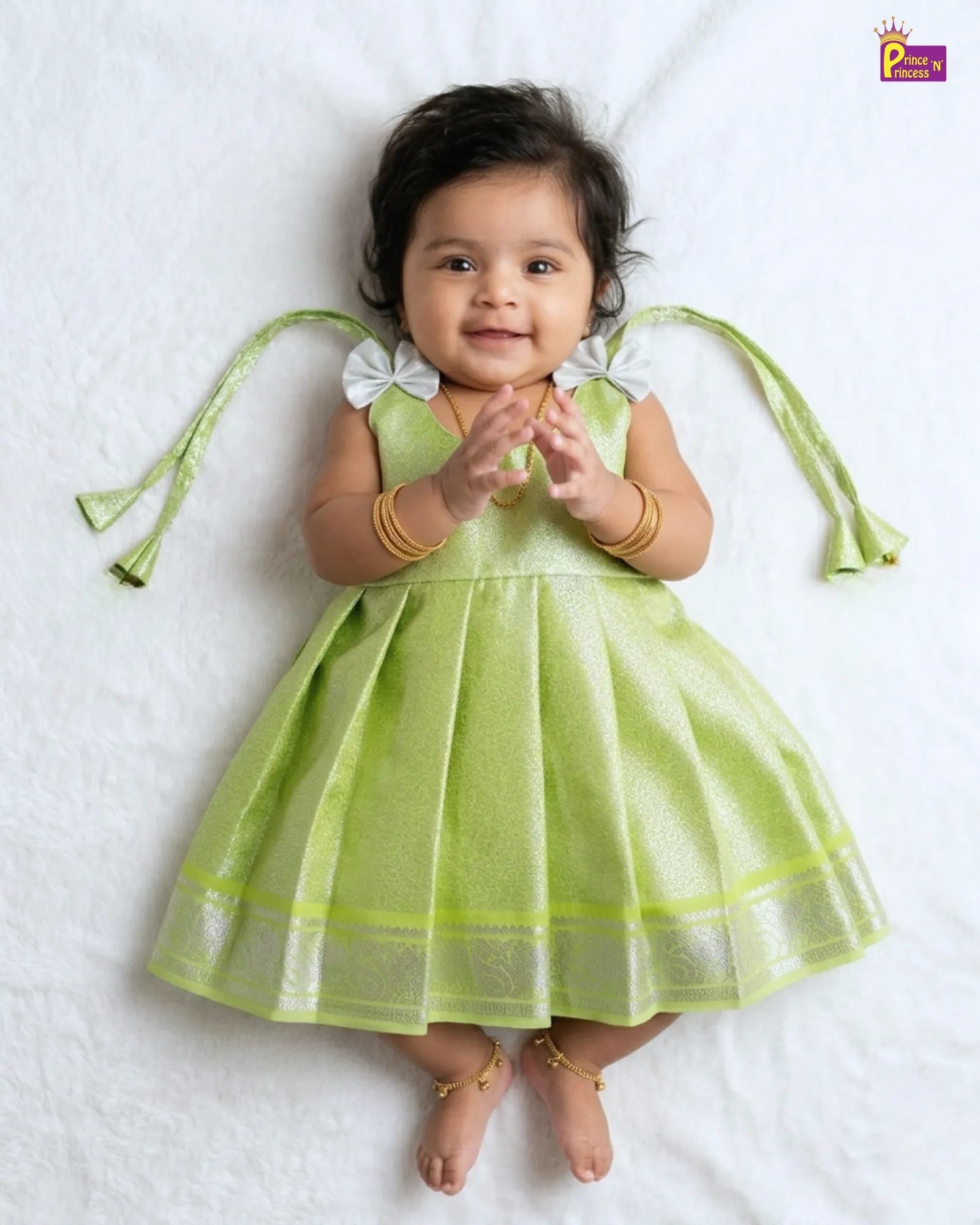 Baby wearing a green dress with angel wings on a white background