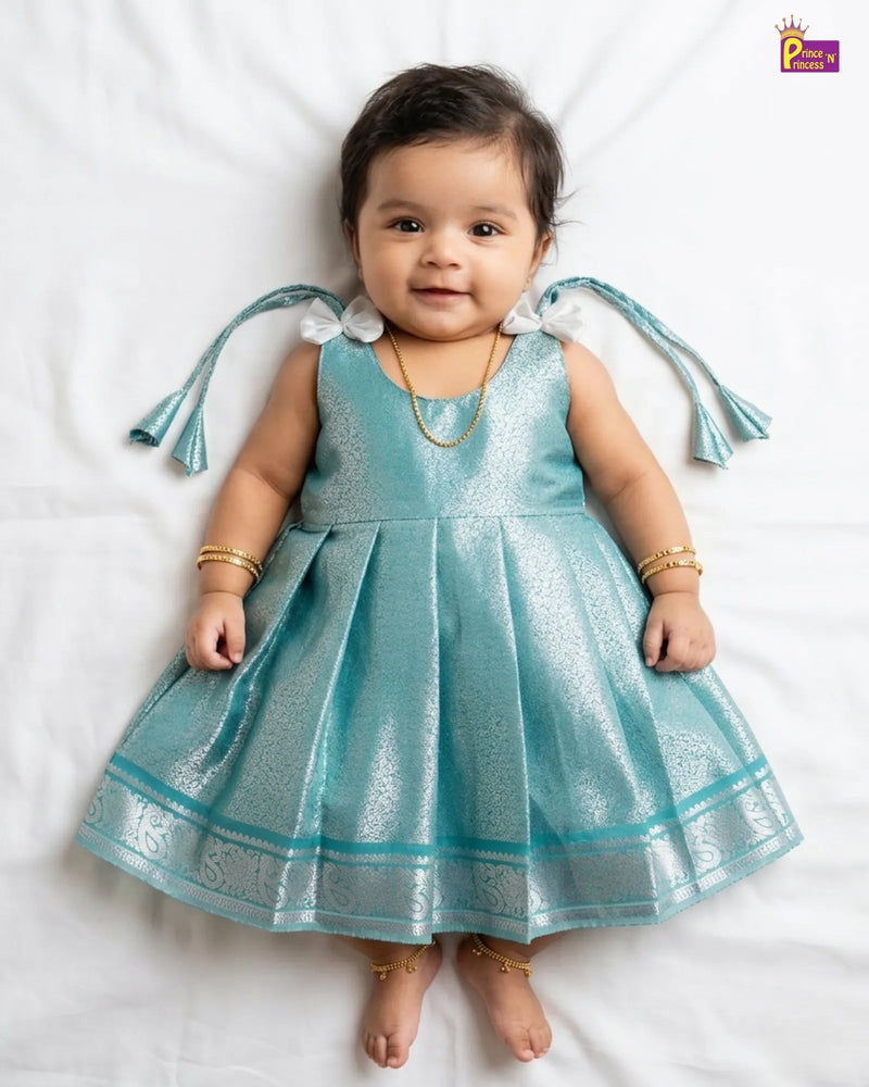 Baby wearing a blue dress with decorative sleeves on a white background