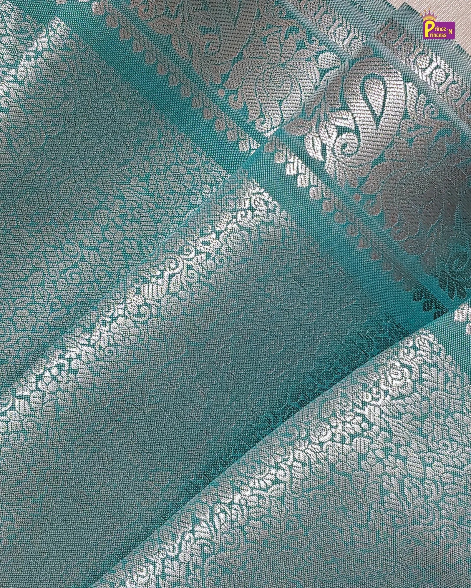 Teal fabric with silver floral patterns and a brand logo in the corner.