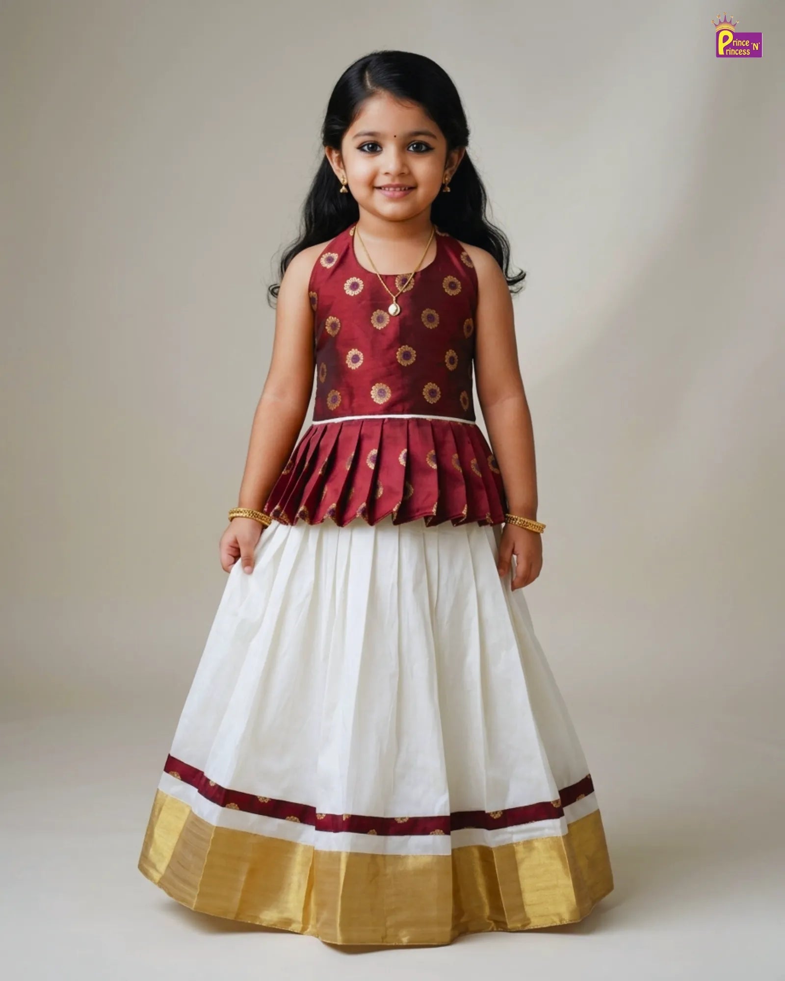 Young girl wearing a traditional outfit with a maroon top and white skirt on a plain background