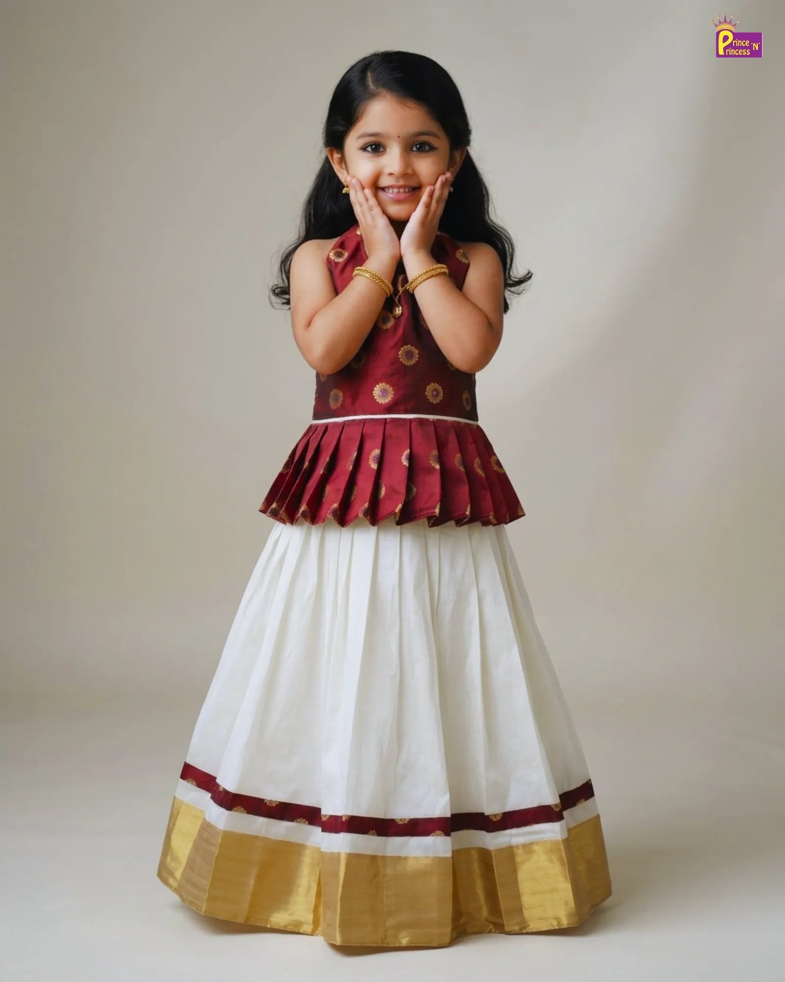 Young girl wearing a traditional outfit with a maroon top and white skirt on a plain background