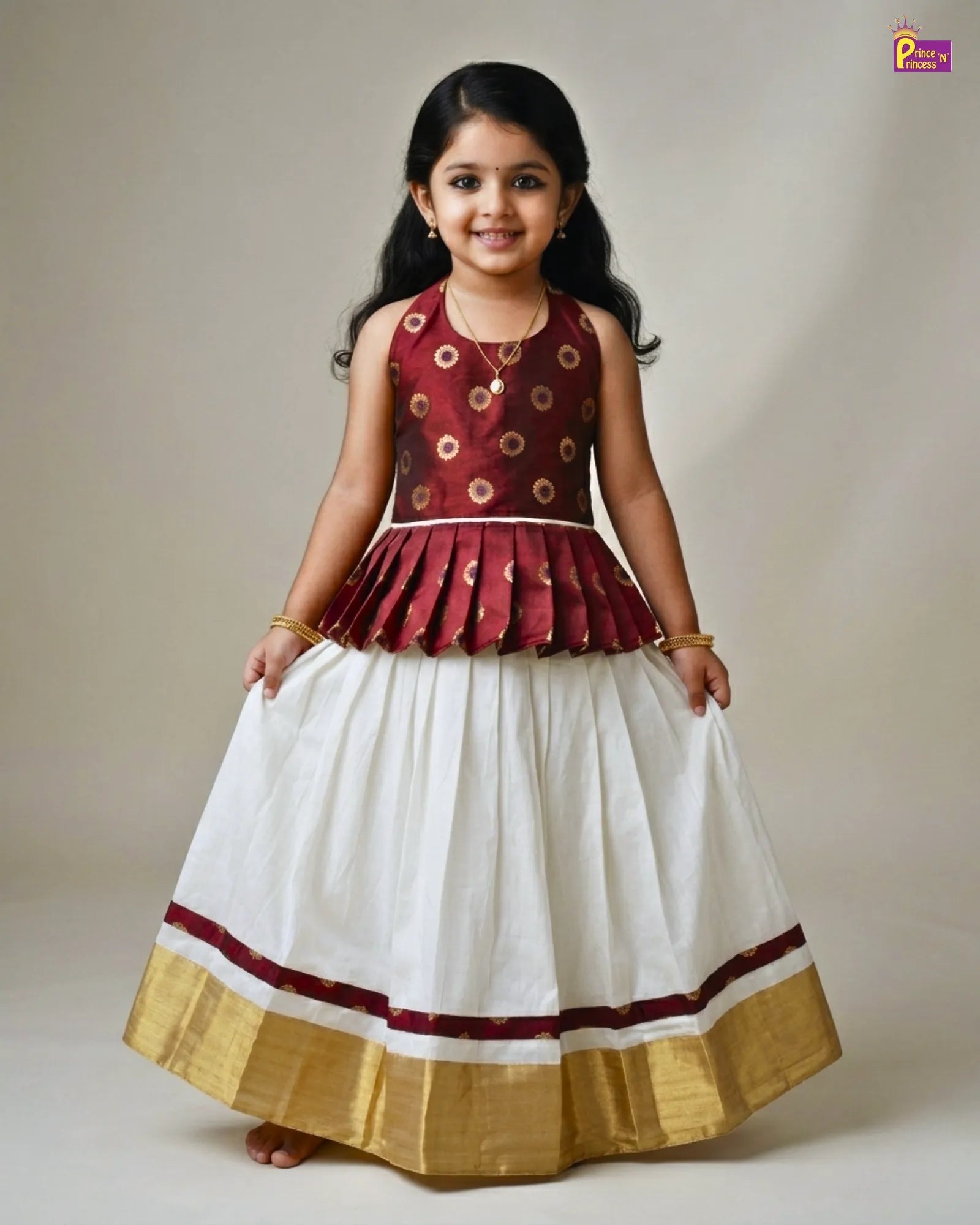 Young girl wearing a traditional outfit with a maroon top and white skirt on a plain background