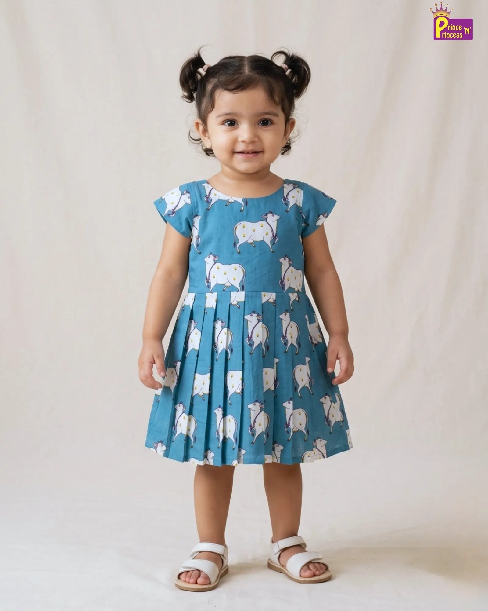 Child wearing a blue dress with animal pattern on a plain background