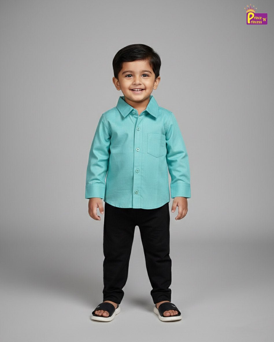Young boy wearing a teal shirt and black pants on a gray background - Prince N Princess