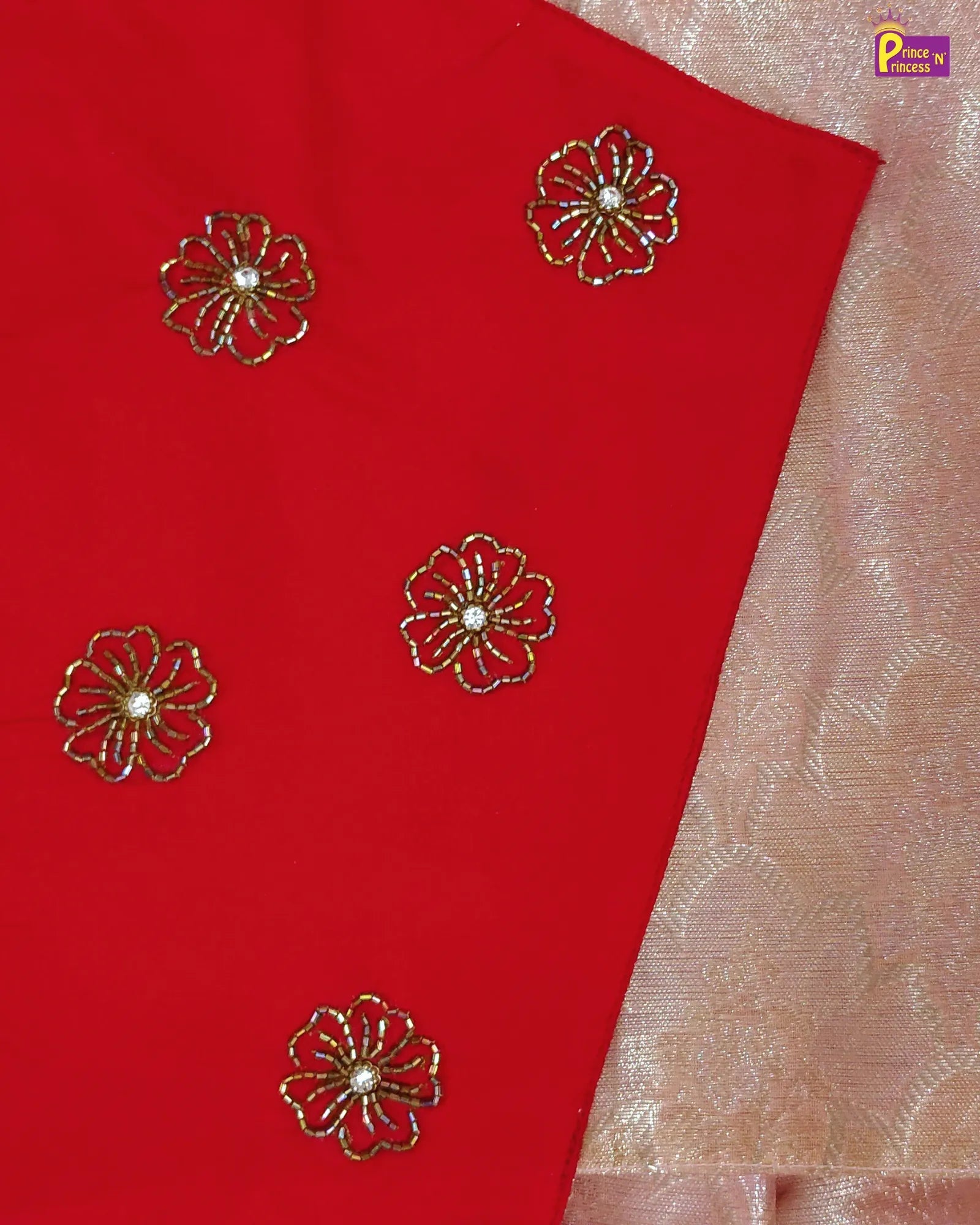 Red fabric with gold floral embroidery on a beige background