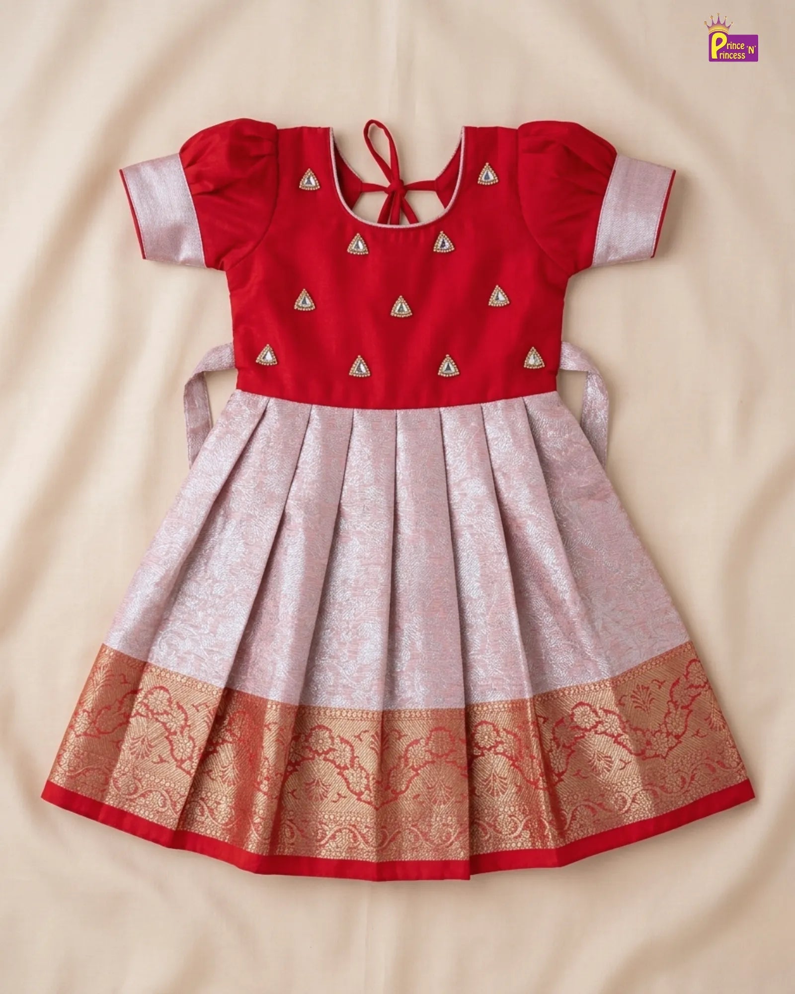 Red and beige traditional dress with intricate patterns on a beige background