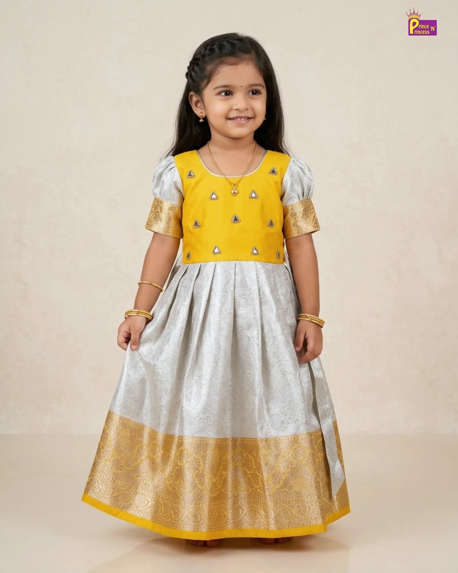 Young girl wearing a yellow and white traditional outfit with gold accents on a beige background