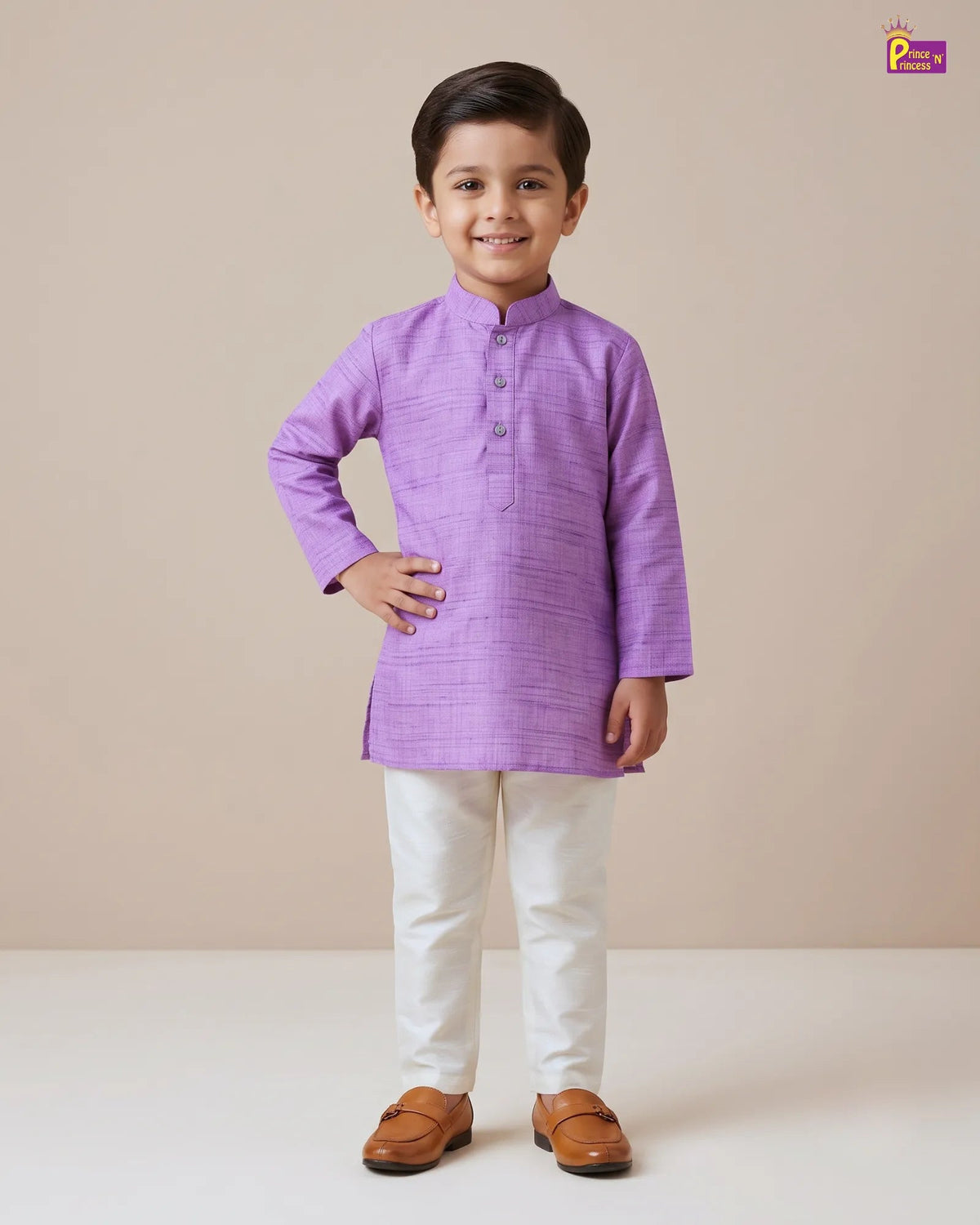 A young boy modeling a light purple kurta with white trousers and brown shoes, standing against a solid beige studio background.
