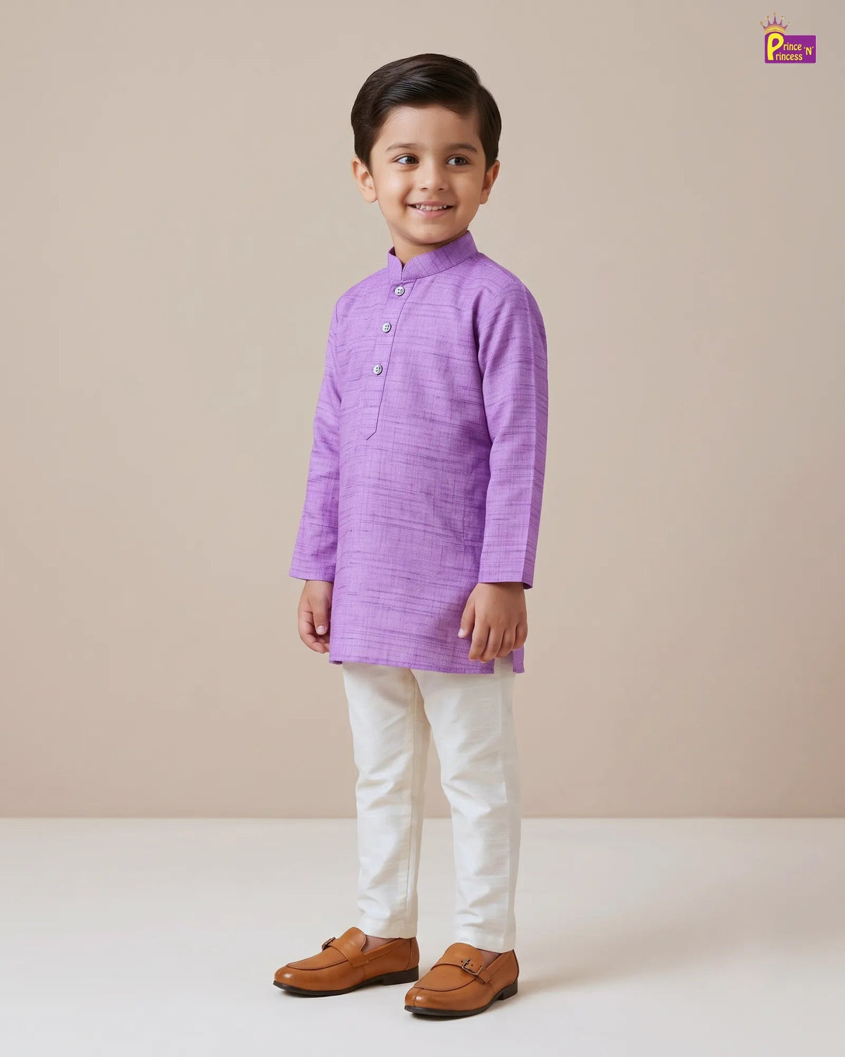 A young boy modeling a light purple textured kurta with white trousers and brown leather loafers, standing against a solid beige studio background.