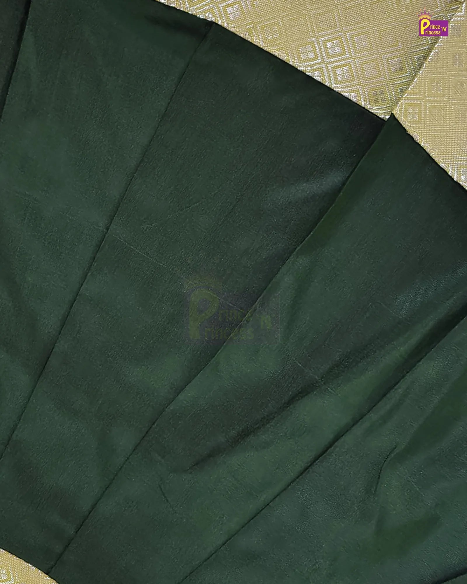 A close-up of a dark forest green fabric, likely a saree, draped diagonally over a beige patterned textile.