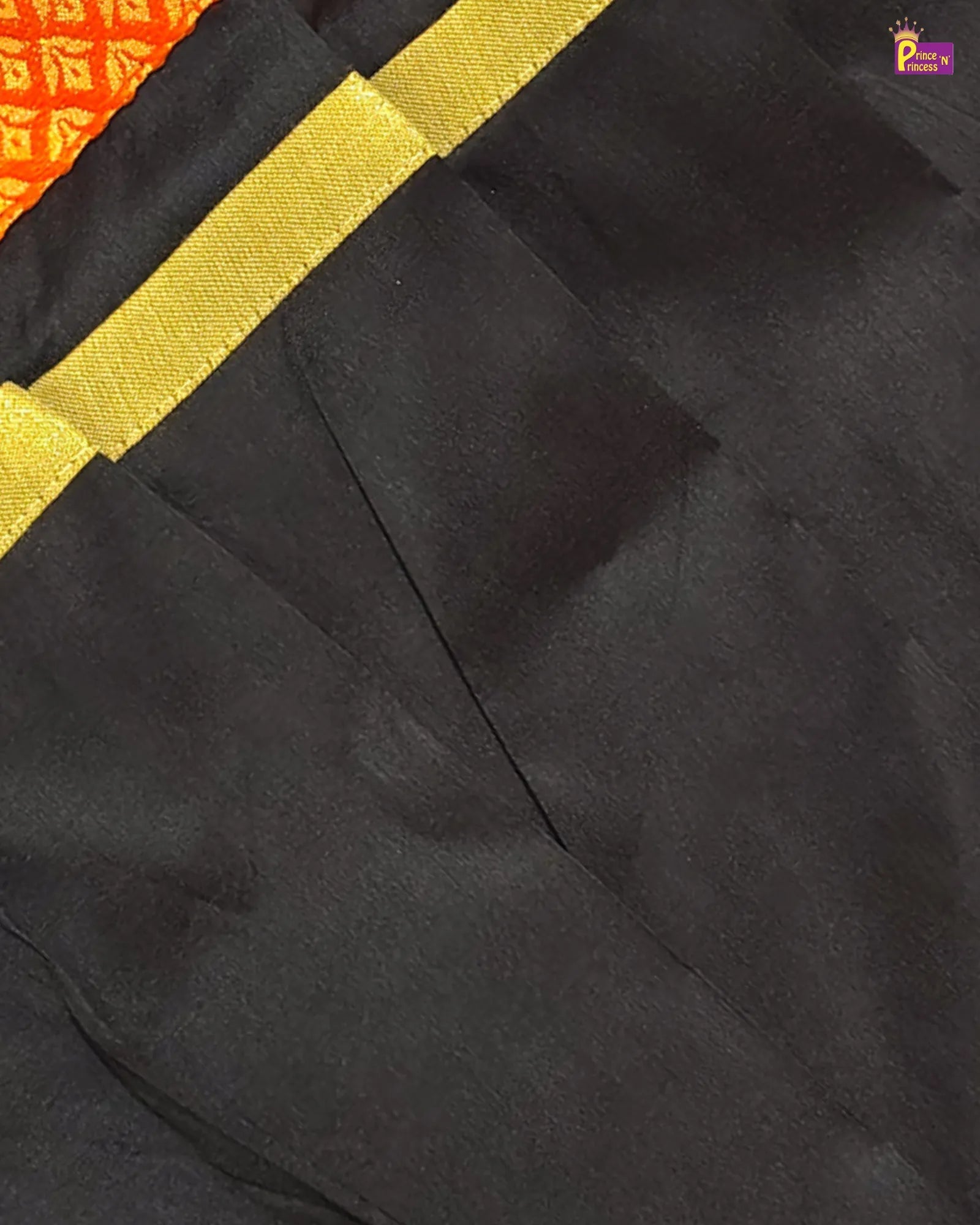 Black fabric with yellow ribbon on a partially visible orange and red background