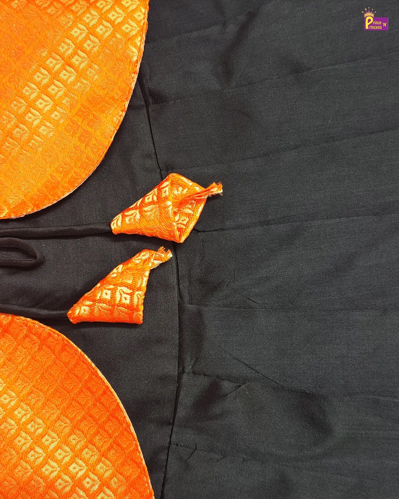 Black fabric with orange decorative patterns on a plain background