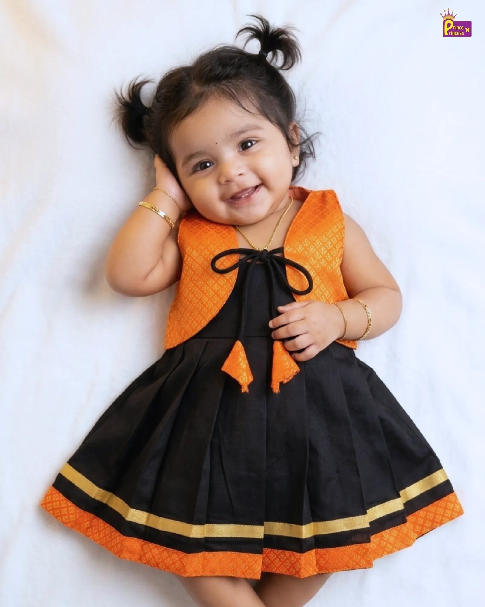 Child wearing a black and orange dress with a gold trim on a white background