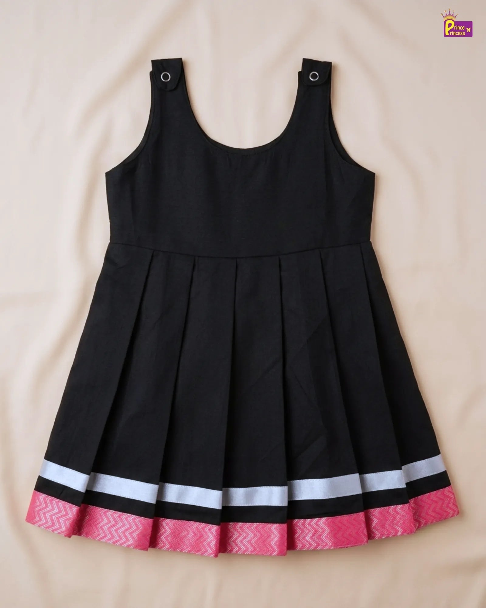 Black dress with pink and white hem on a beige background