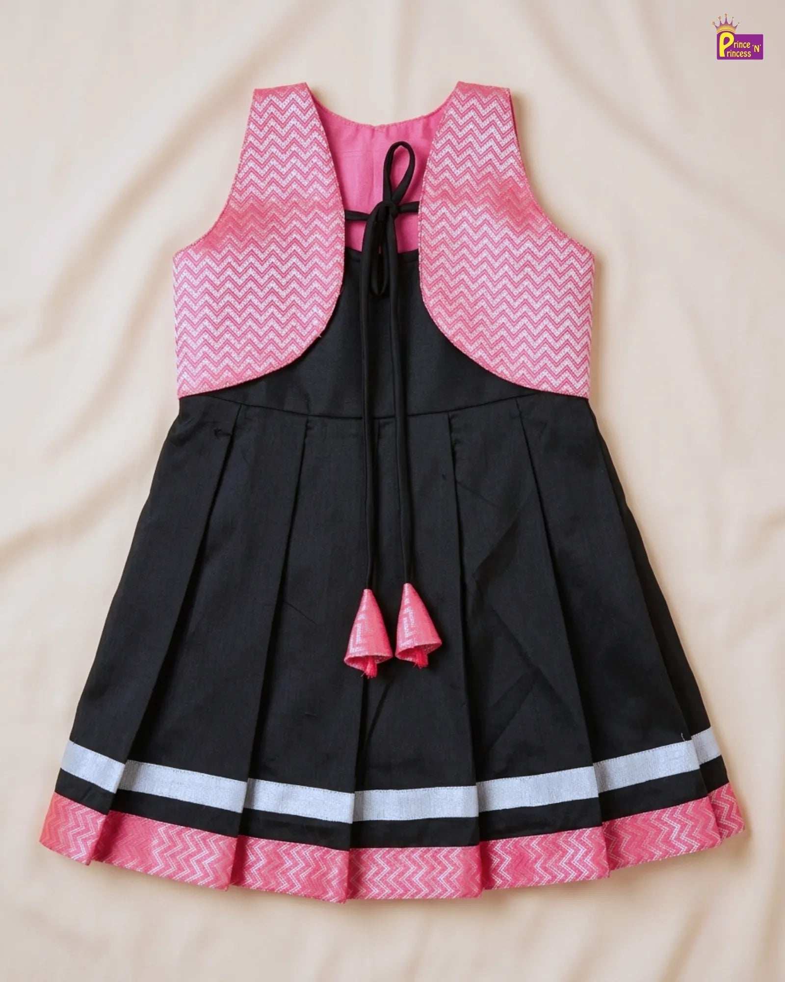 Black dress with pink and white patterned top on a beige background