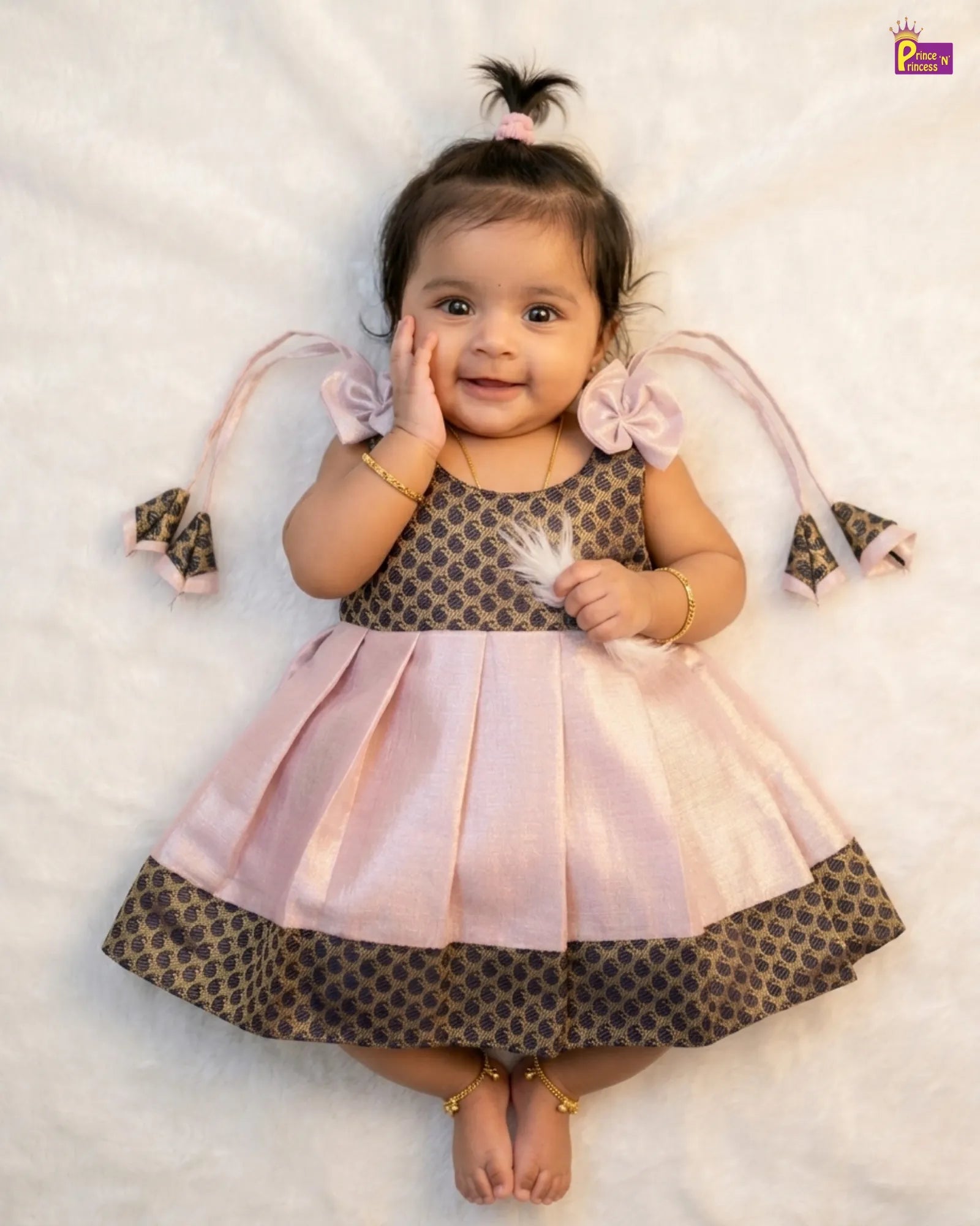 Baby wearing a polka dot dress with pink accents on a light background