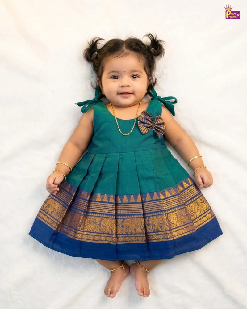 Child wearing a green and blue traditional dress with elephant patterns on a white background