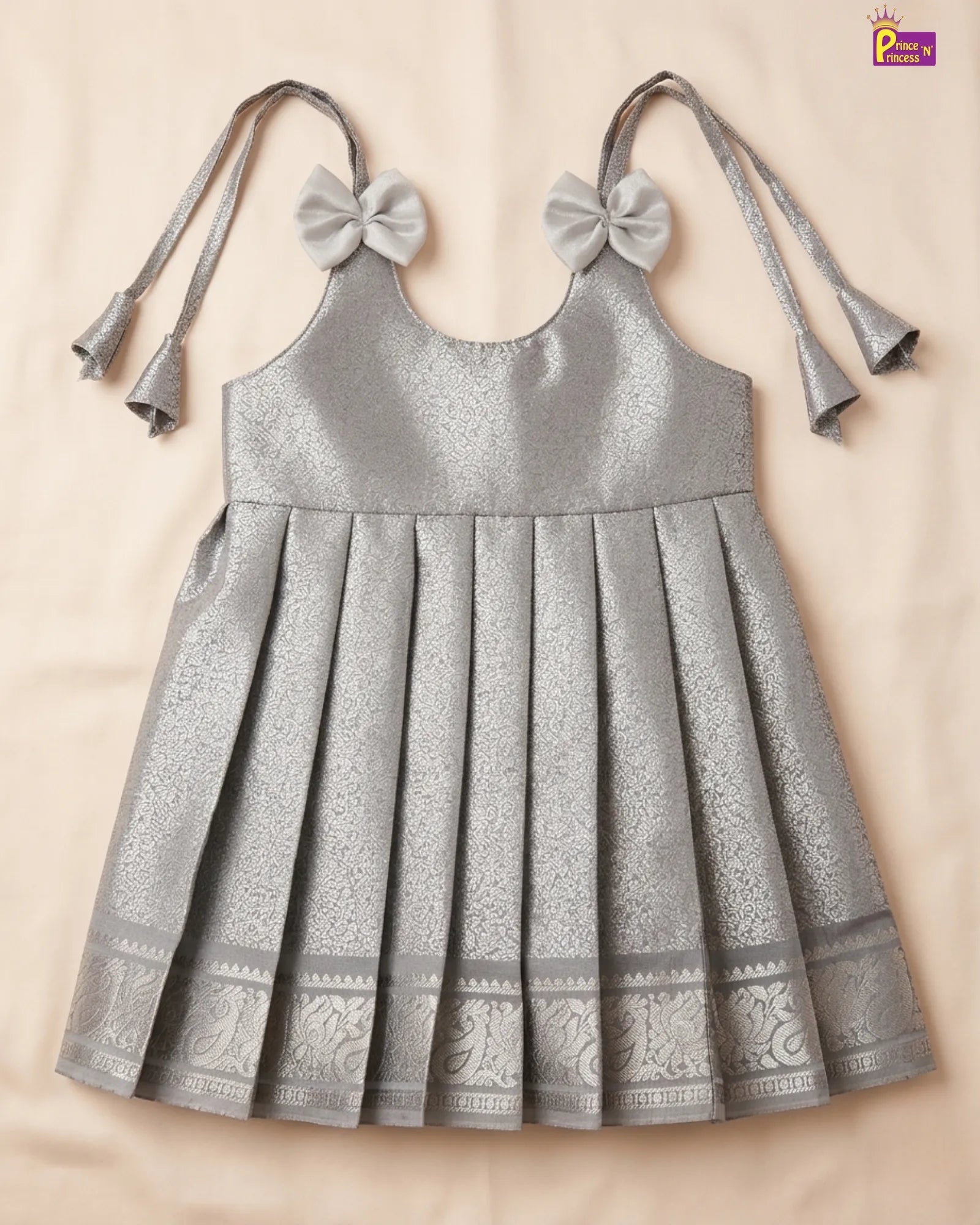 Silver dress with decorative bows on a beige background