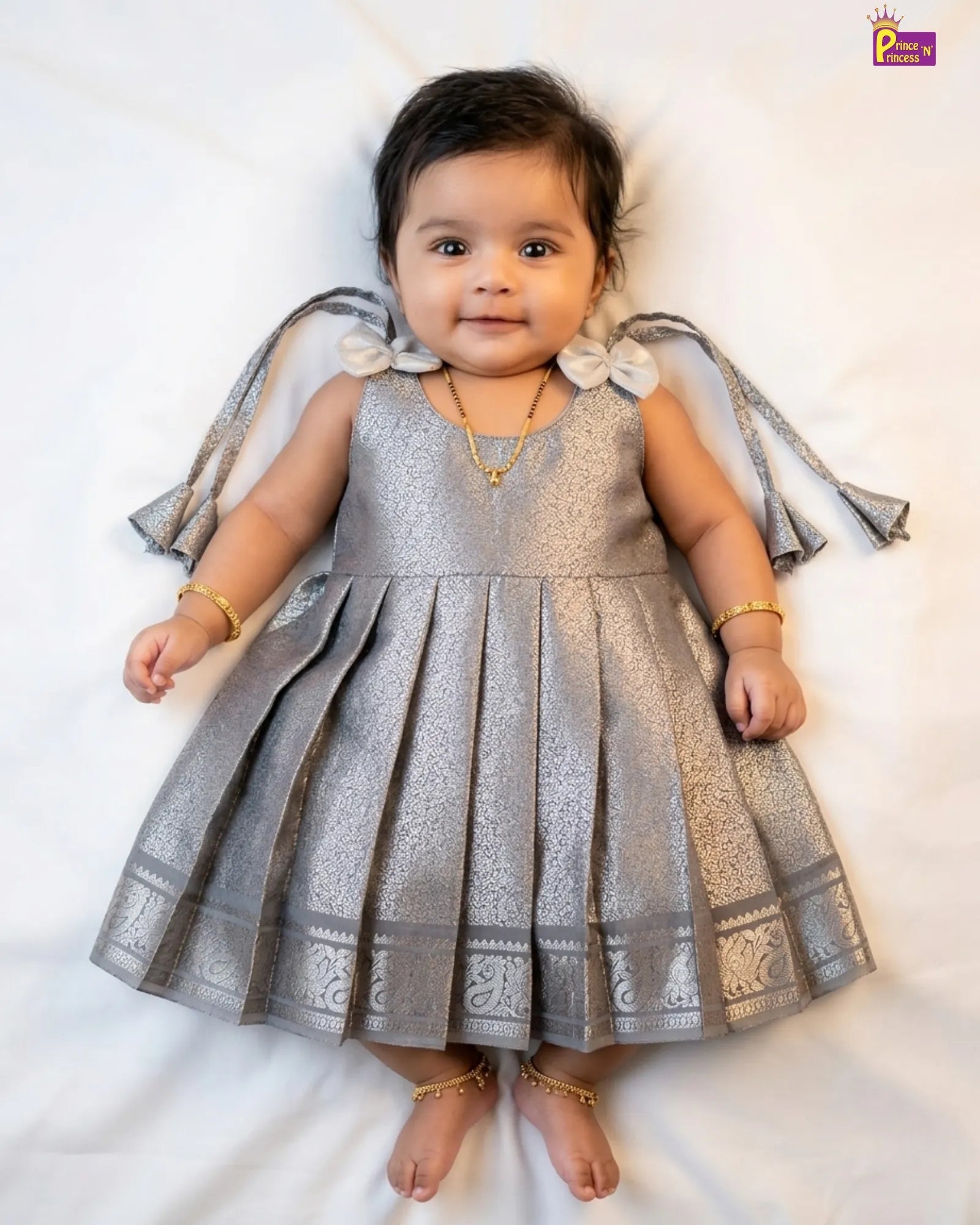 Baby in a silver dress with decorative elements on a white background