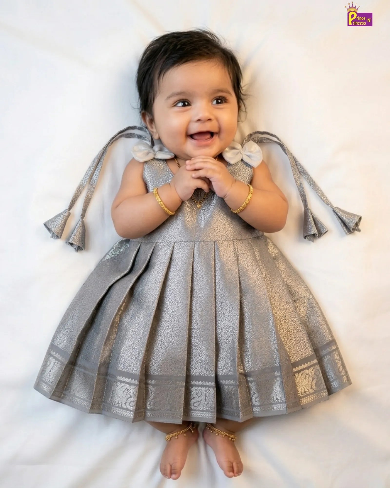 Baby in a silver dress with floral details on a white background