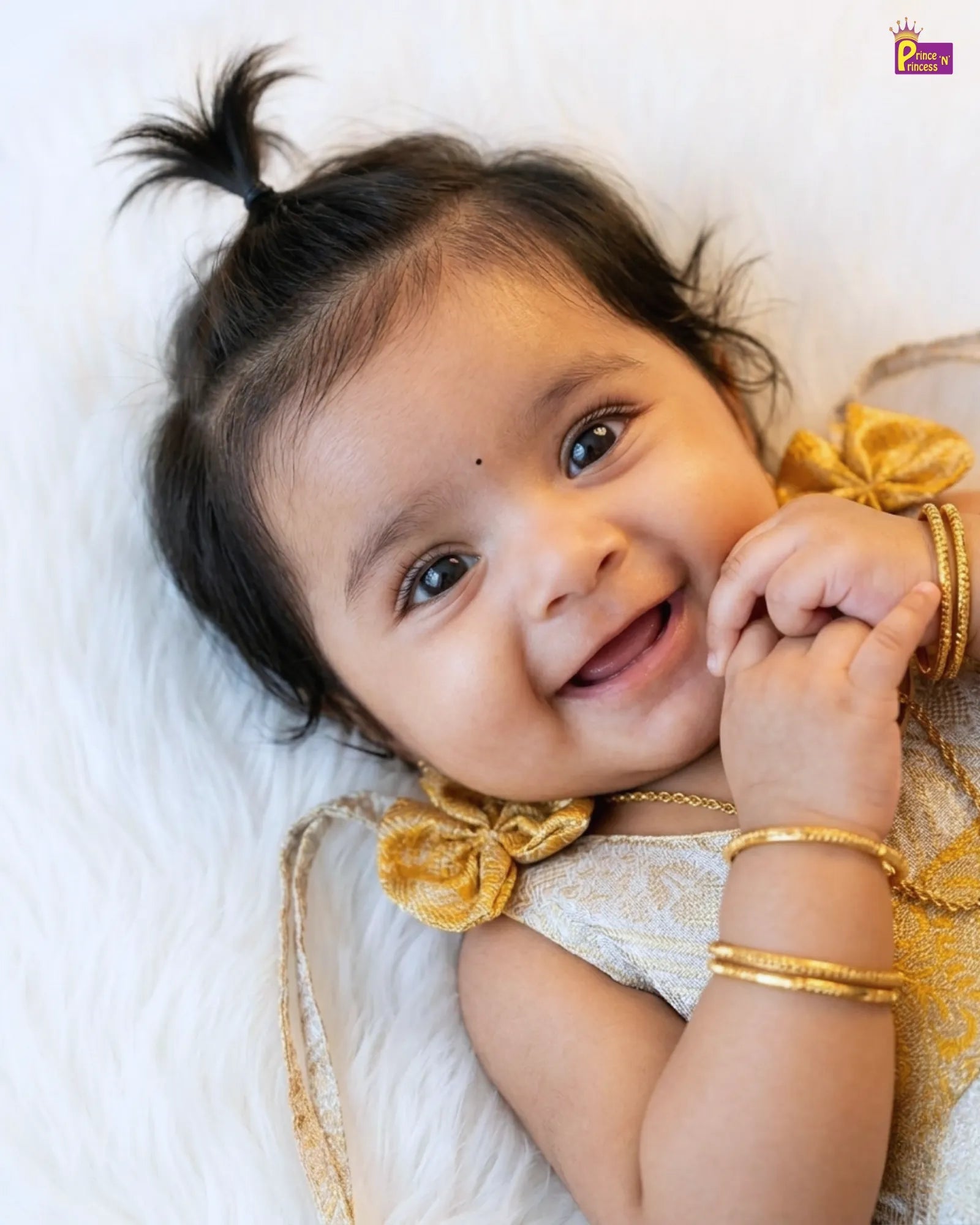 Baby with gold hair ties and bangles on a white background