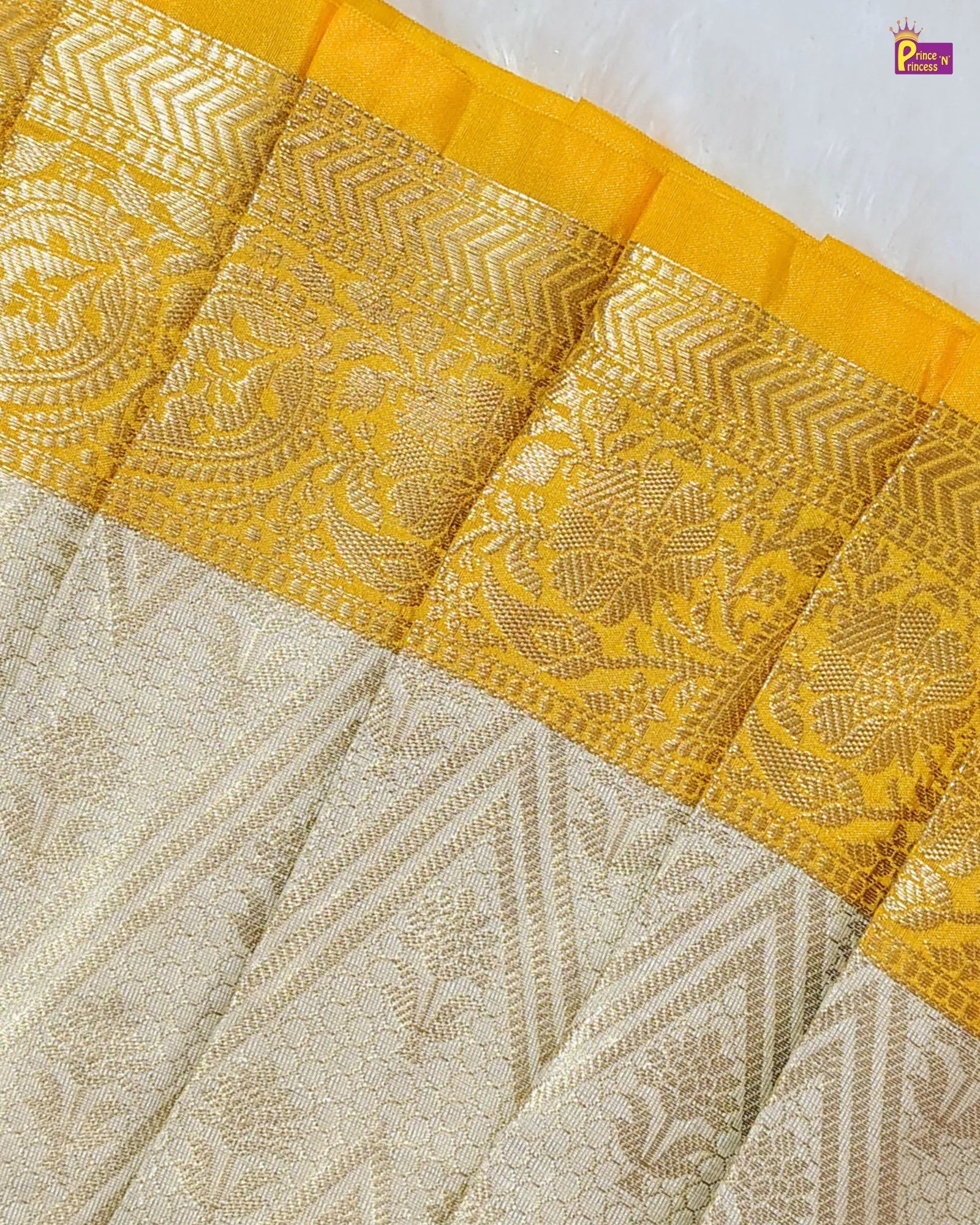 Close-up of a fabric with intricate patterns and yellow border on a white background