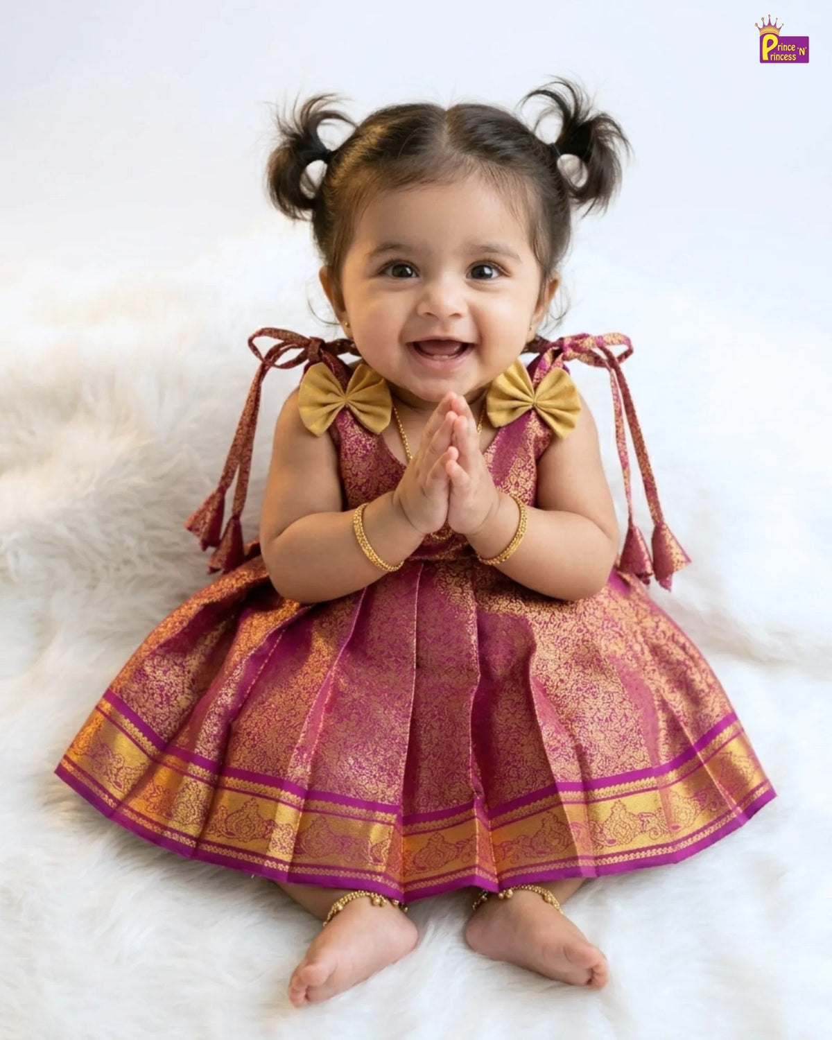 Child wearing a traditional outfit with gold and pink details on a white background