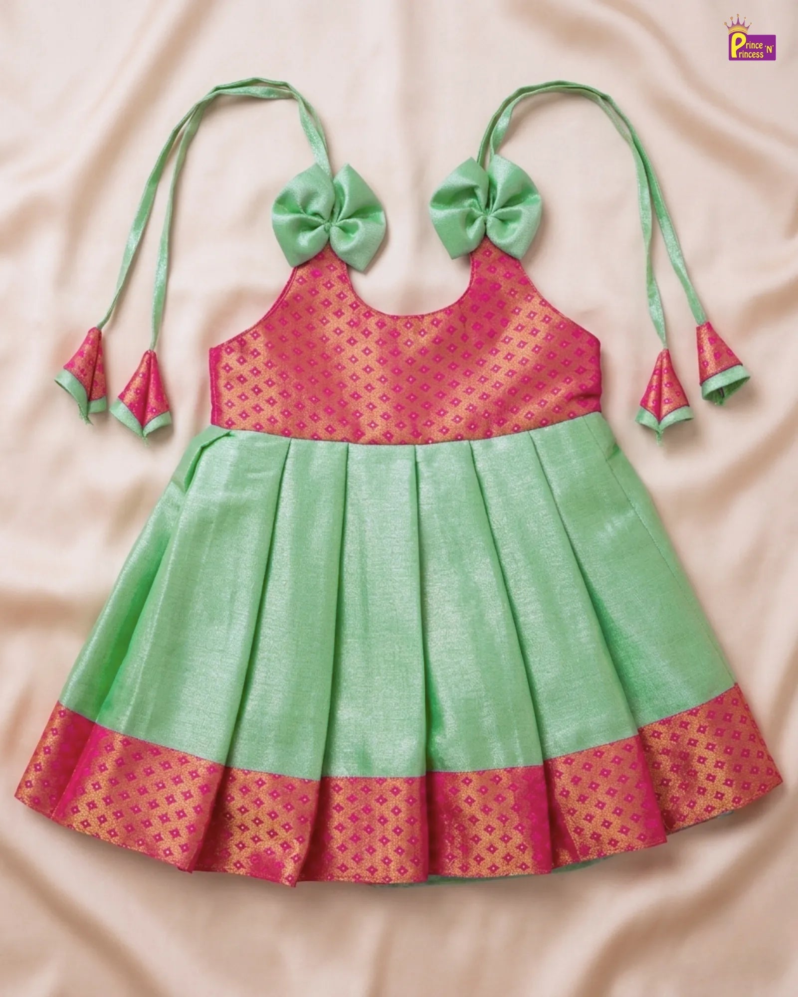 Green and pink children's dress with floral details on a beige background