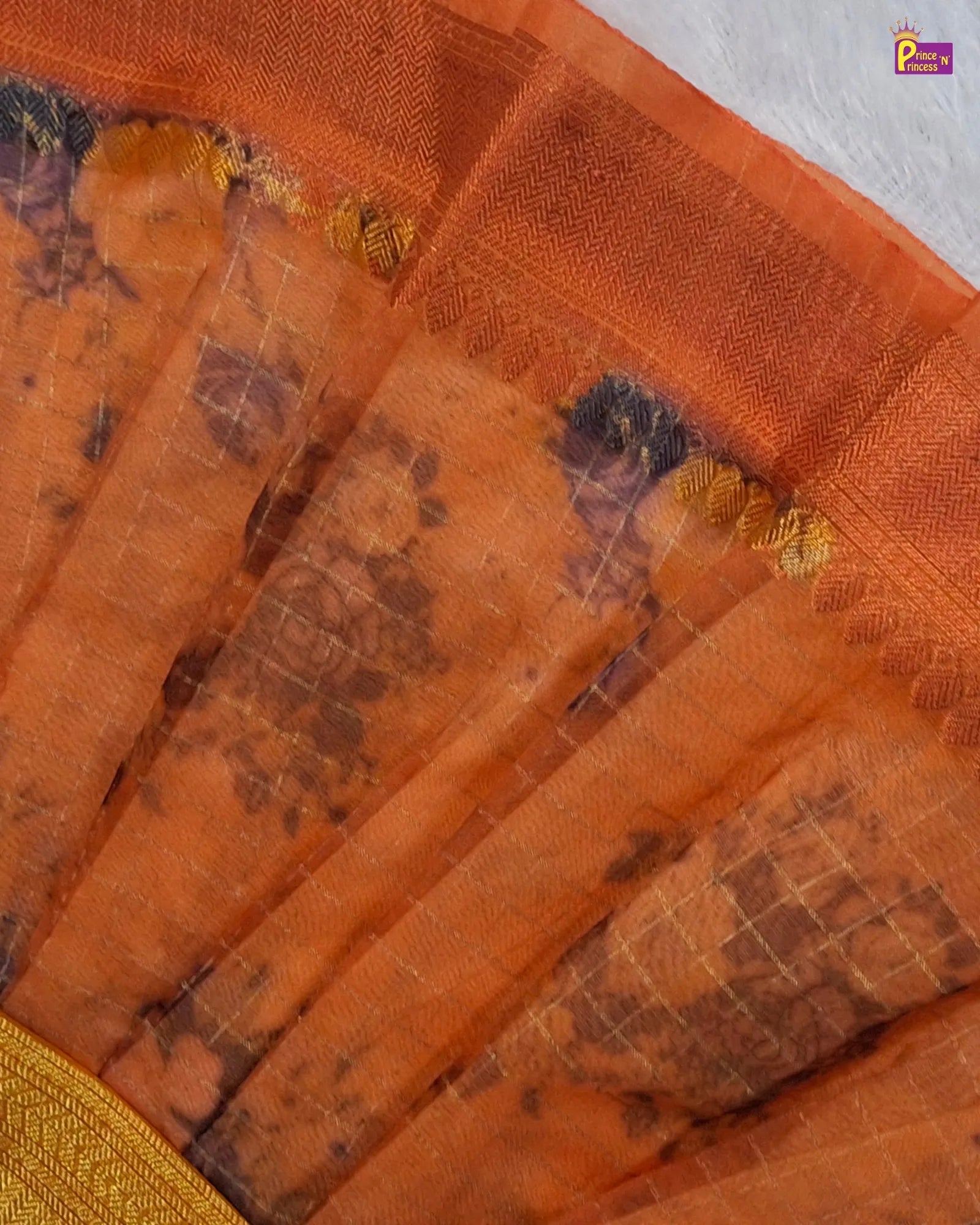 Close-up of an orange fabric with intricate patterns and gold accents.
