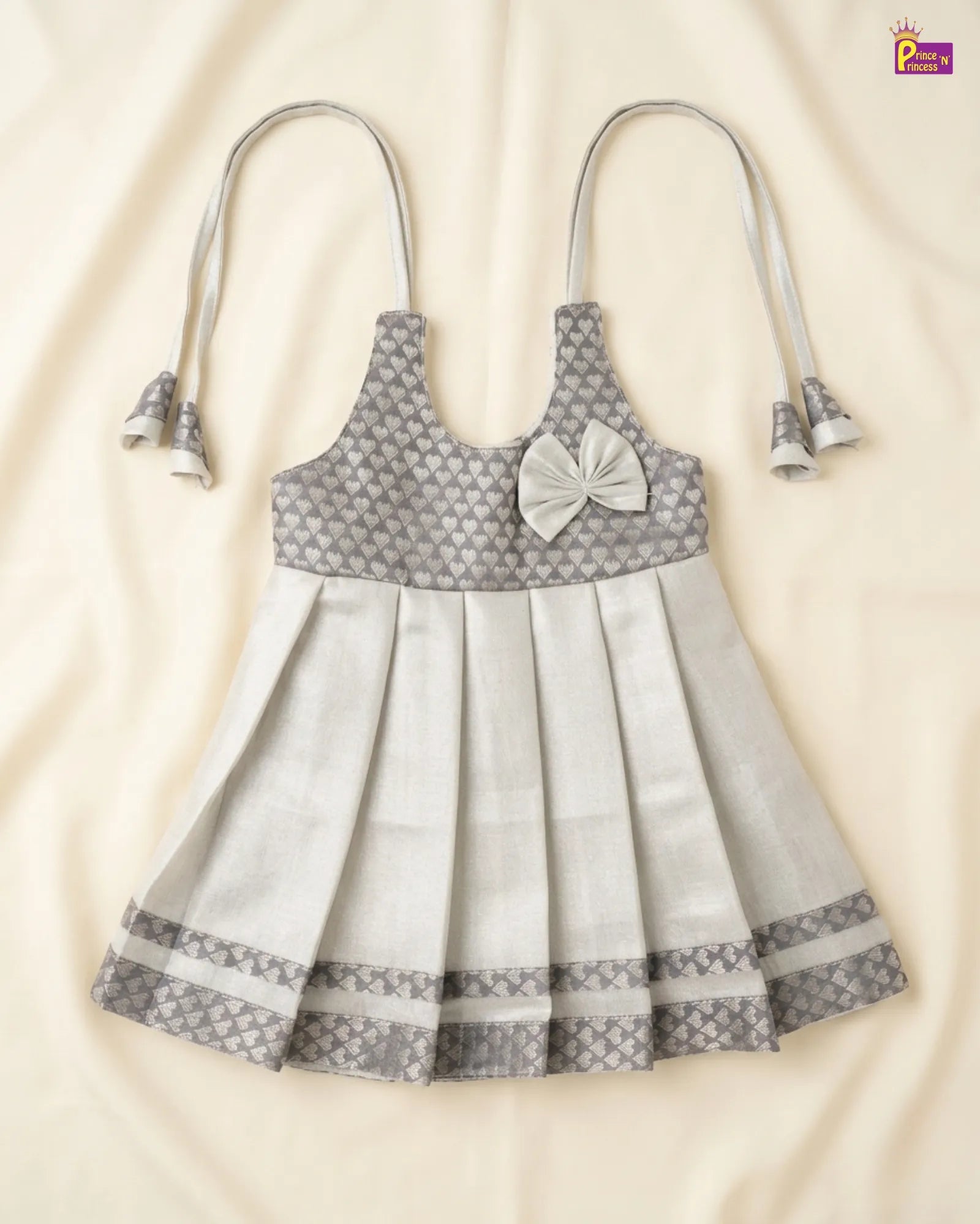 Gray and white patterned dress with bow detail on a beige background