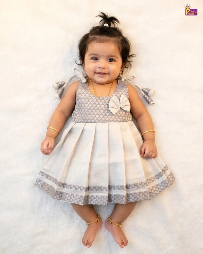 Baby wearing a gray and white dress with a bow on a white background