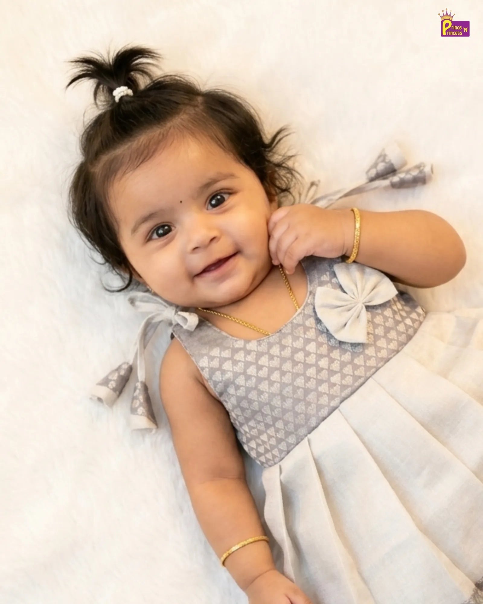 Baby wearing a patterned dress with white accents on a light background