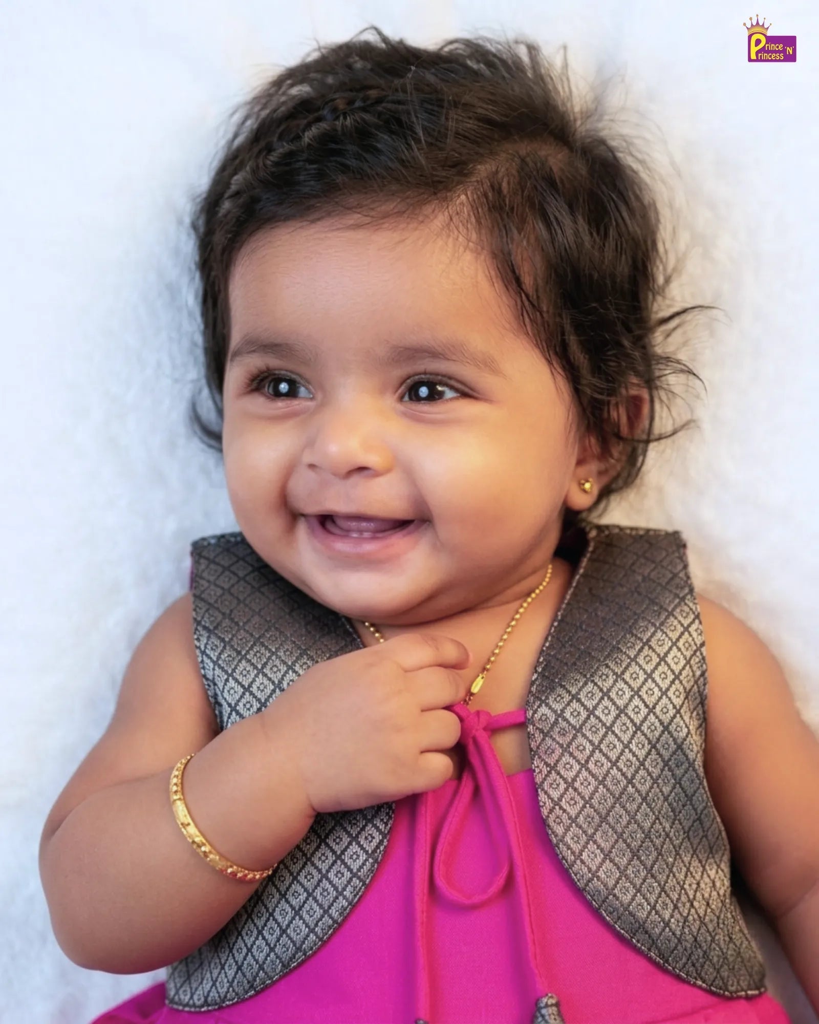Baby wearing a pink dress with a gray vest on a white background