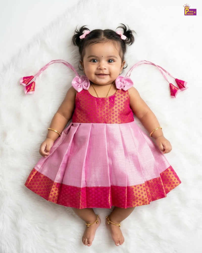 Baby in a pink and red traditional outfit with decorative hair accessories on a white background