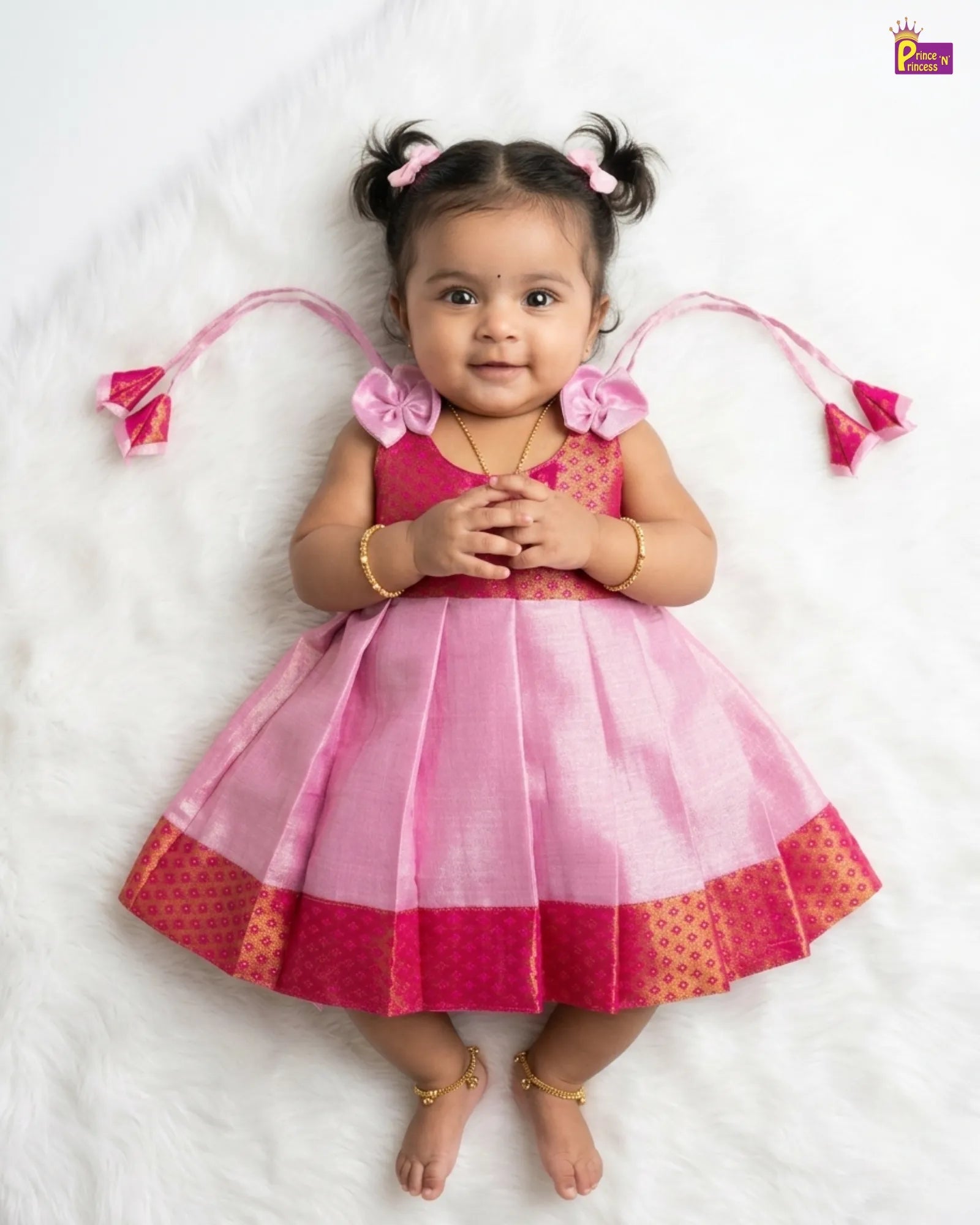 Young child wearing a pink and red dress with decorative elements on a white background