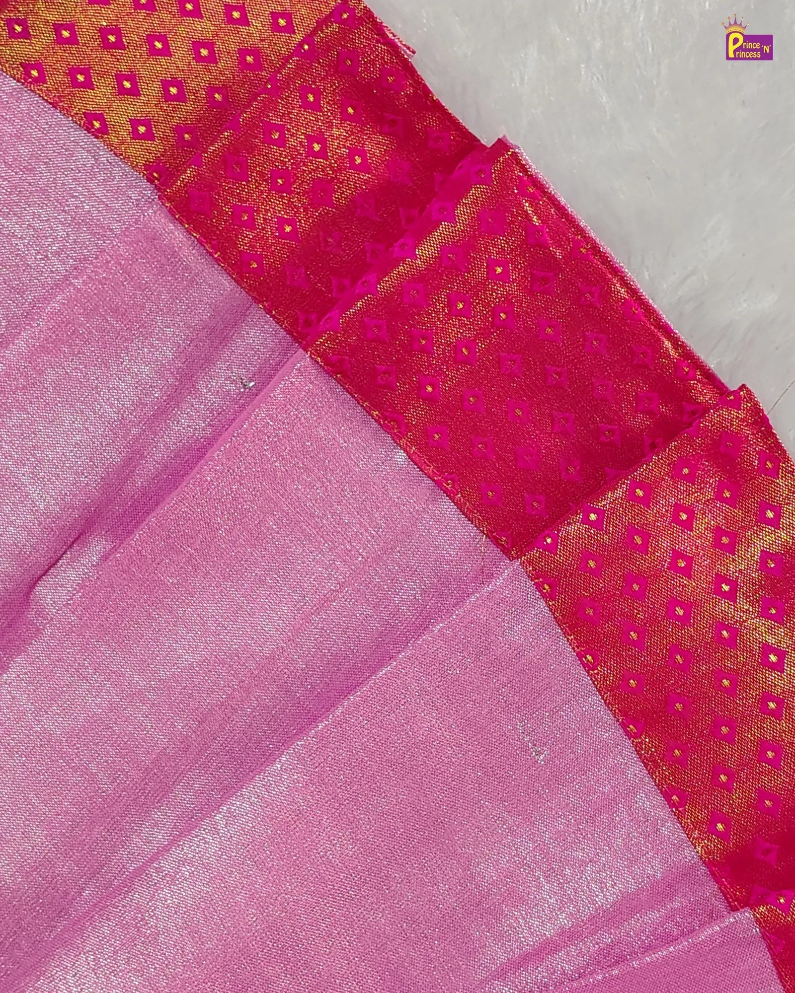 Close-up of a pink fabric with a gold pattern on a textured surface