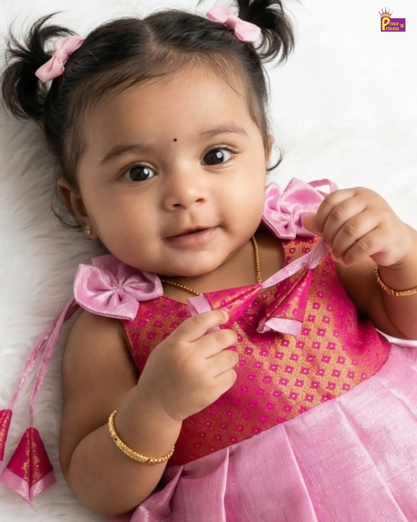 Baby in a pink dress with decorative elements on a white background