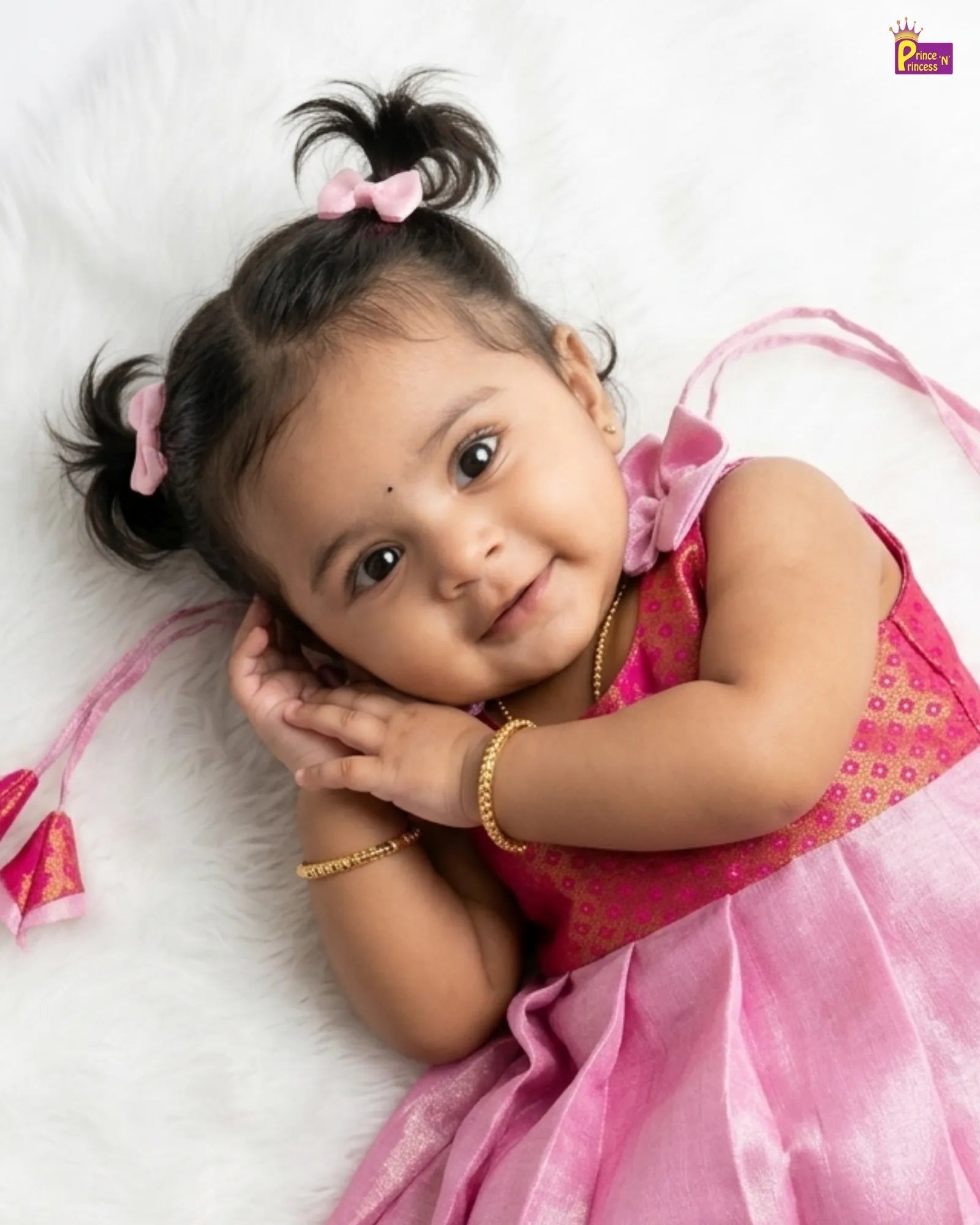 Young child in a pink dress with hair bows on a white background