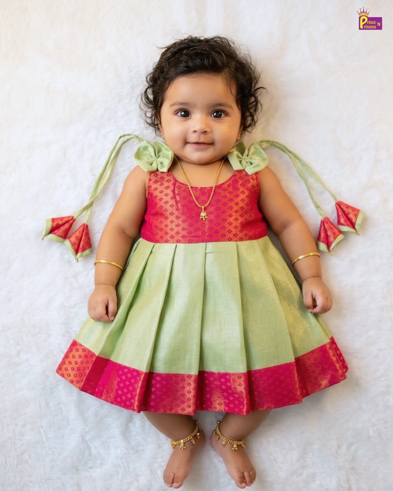 Baby wearing a colorful dress with watermelon designs on a white background